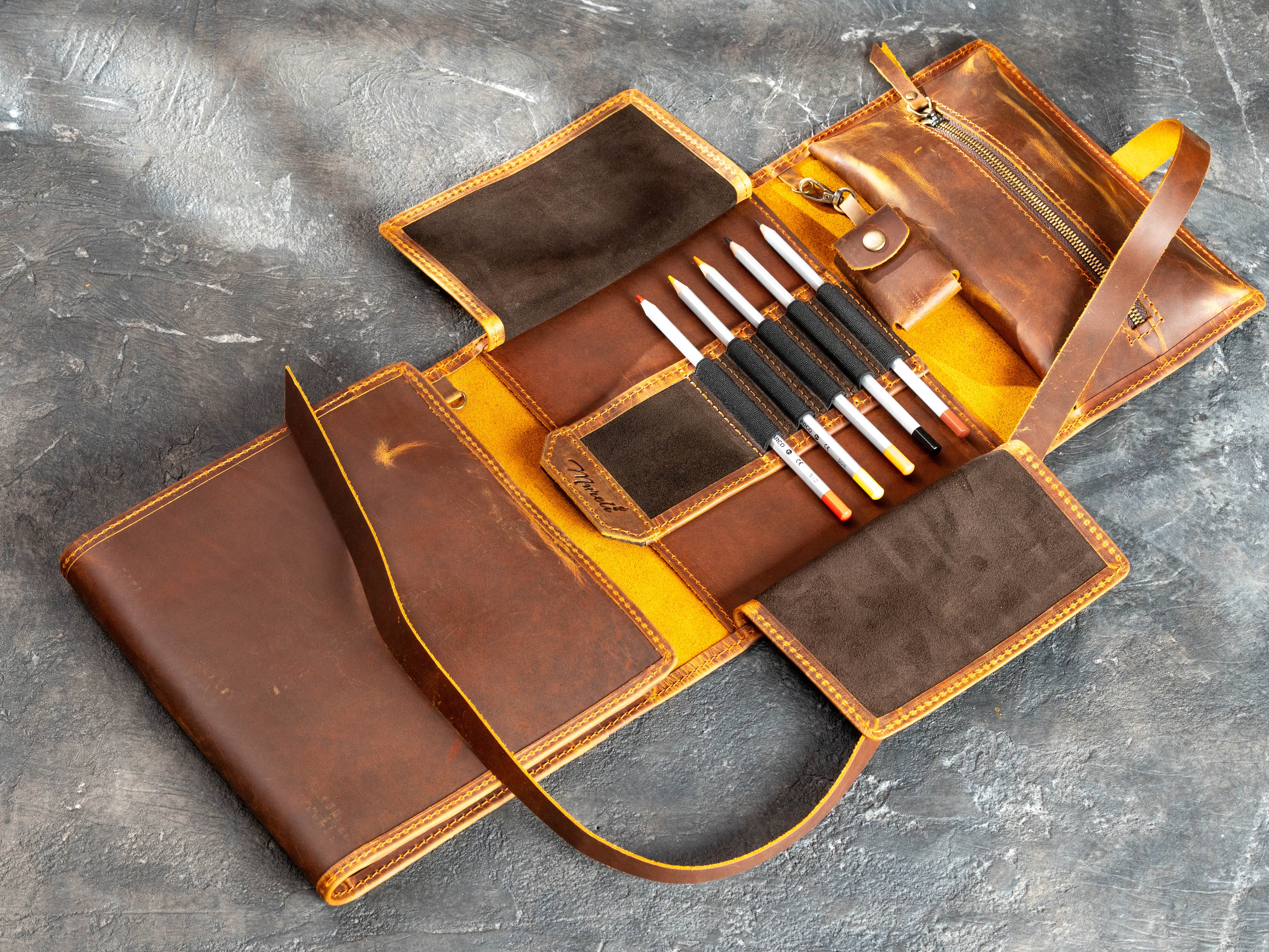Leather artist organizer with empty central A5 sketchbook holder, pencil storage, suede flaps, and zippered compartment