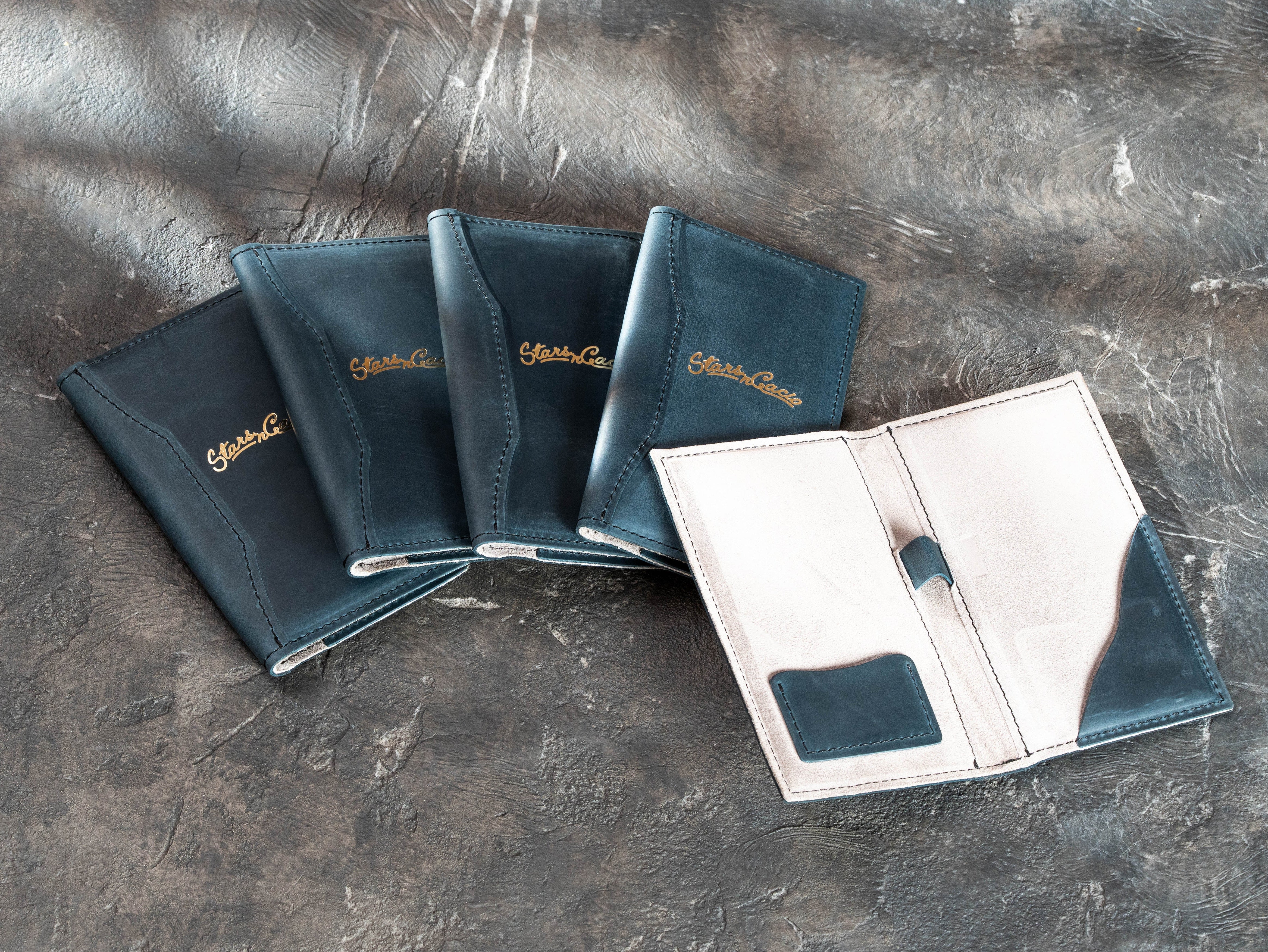 Blue leather restaurant check presenters with gold foil branding and stitched curved cover details