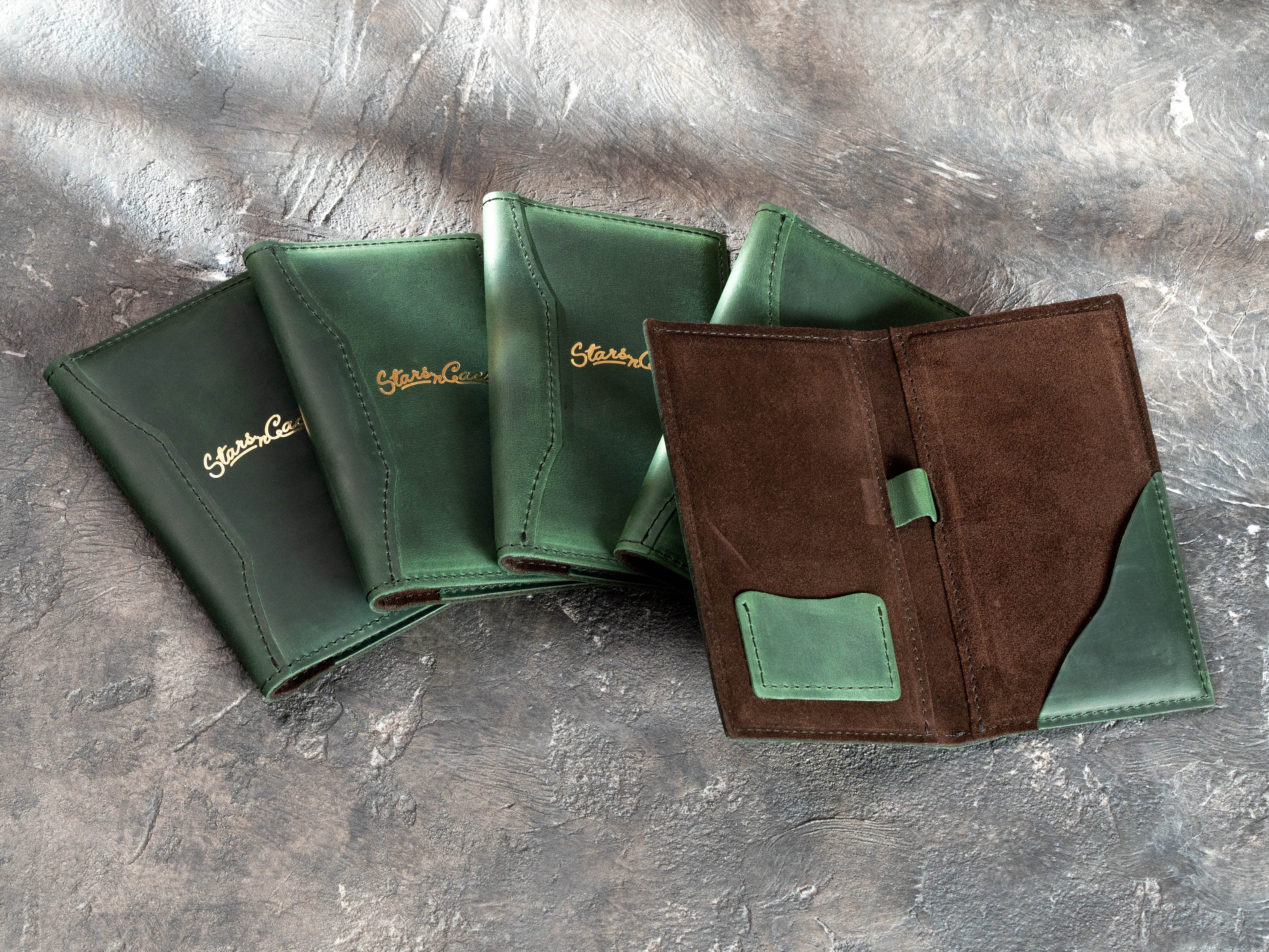 Green leather restaurant check presenter with gold foil branding and brown suede lining