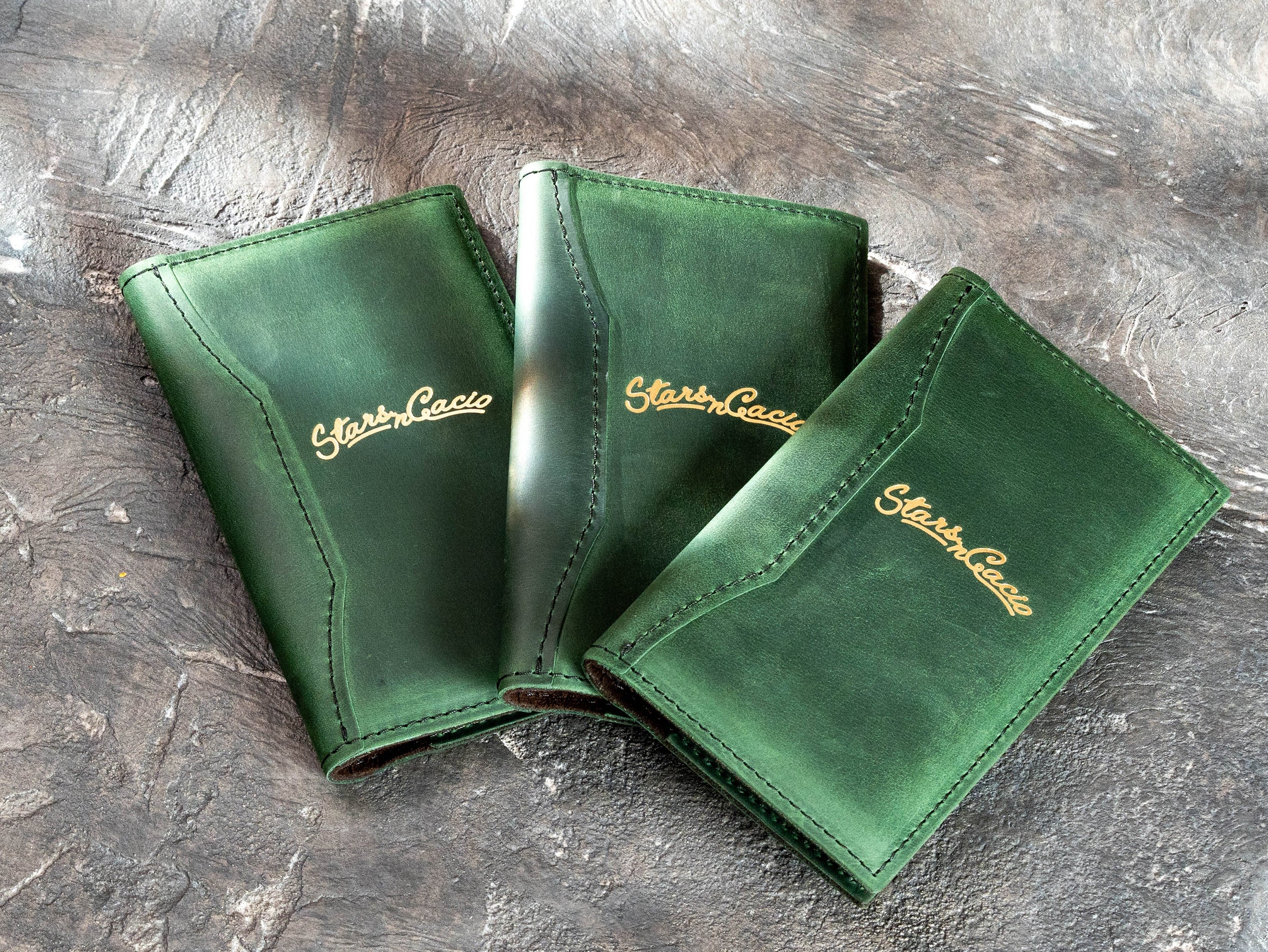 Group of personalized green leather restaurant bill holders with stitched edges and gold foil branding