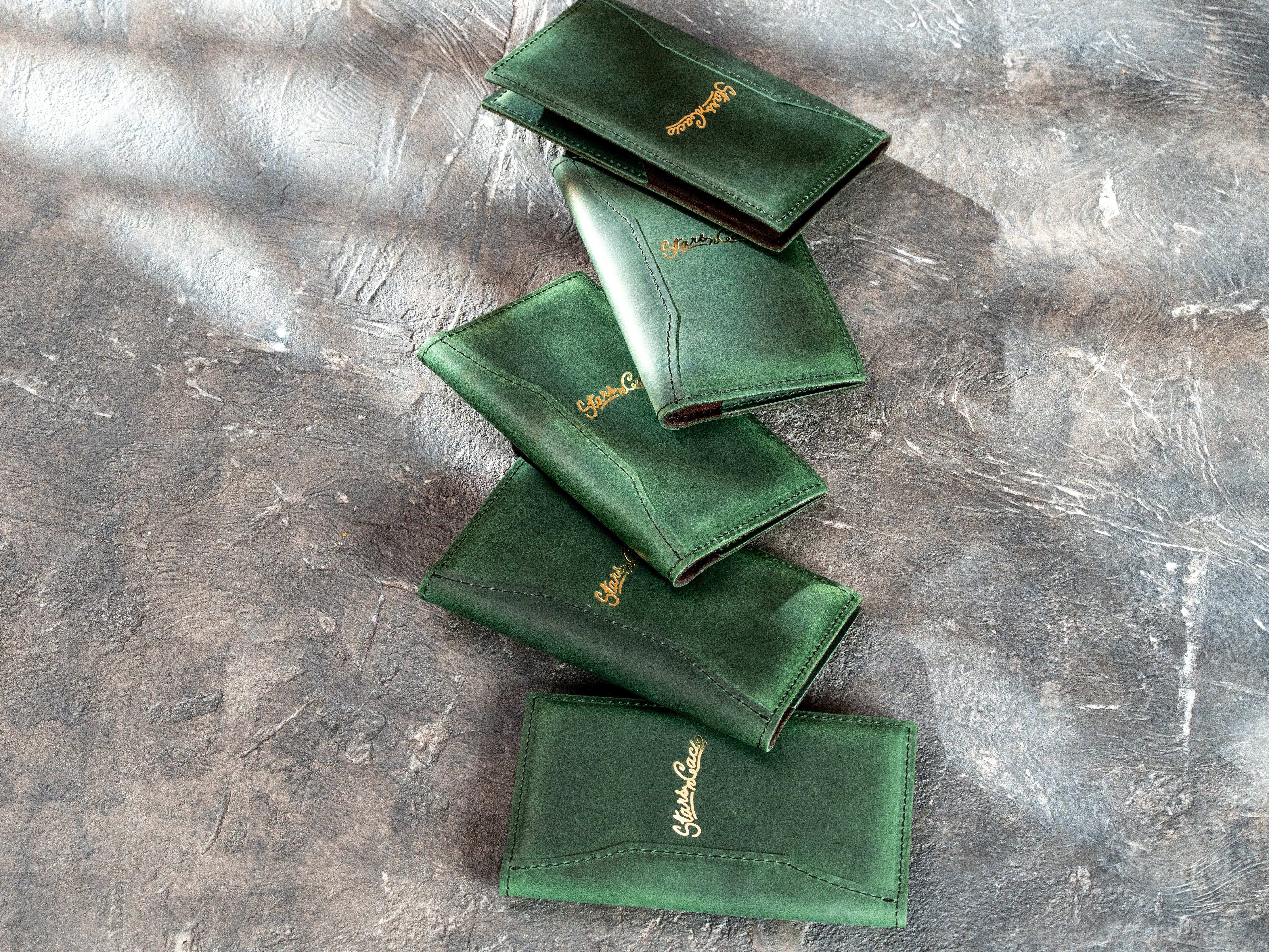 Stacked green Crazy Horse leather check presenters with custom gold foil restaurant logos