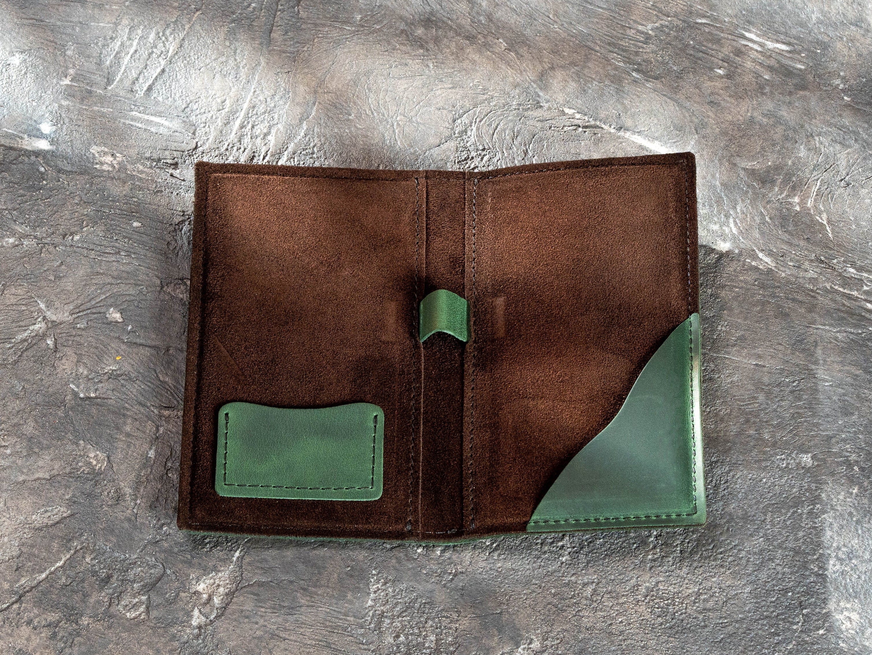 Brown suede interior of a green leather bill holder with card pocket, pen holder, and receipt pocket