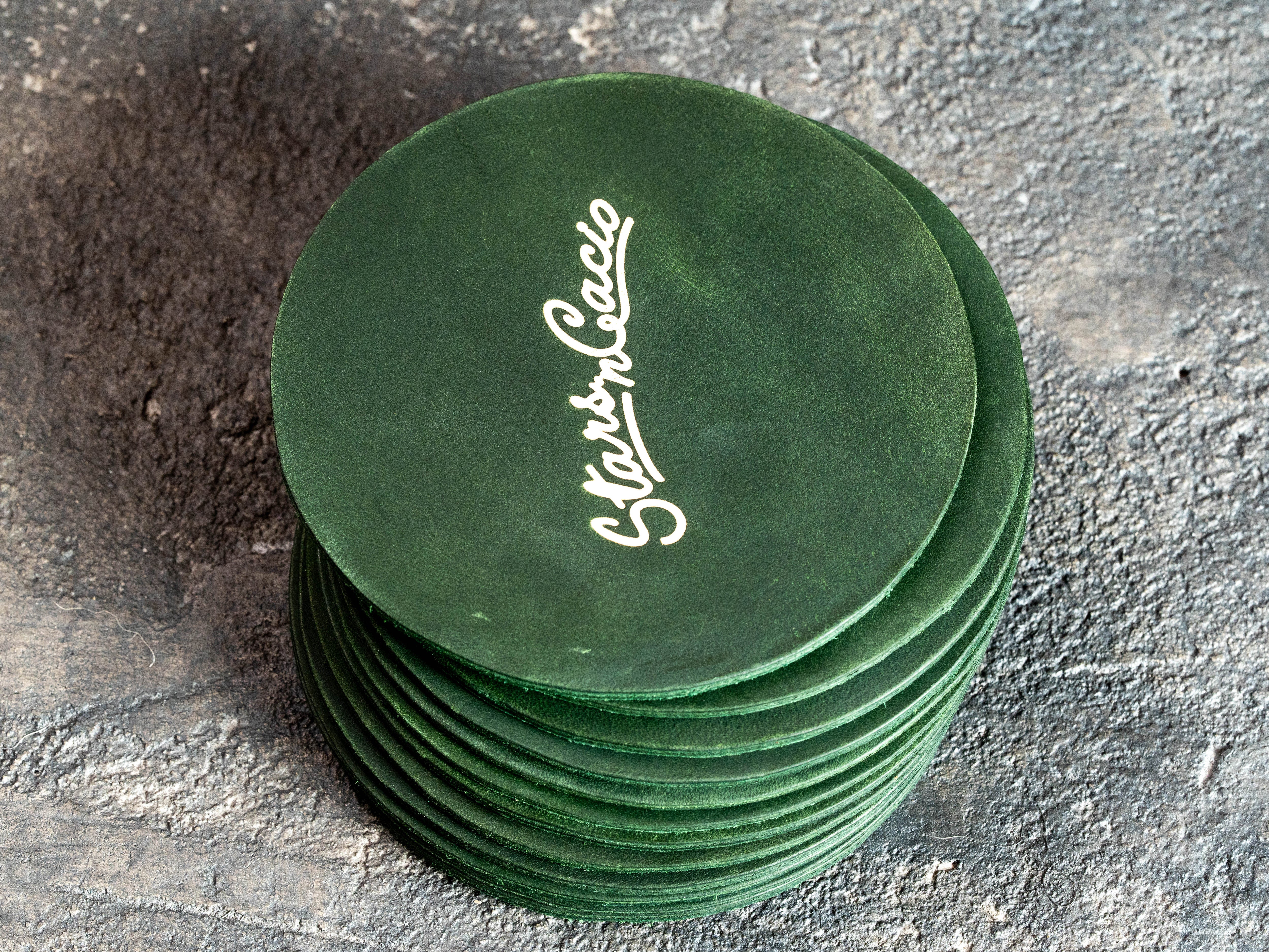 Stack of custom green Crazy Horse leather coasters with gold foil Star in Cacio logo