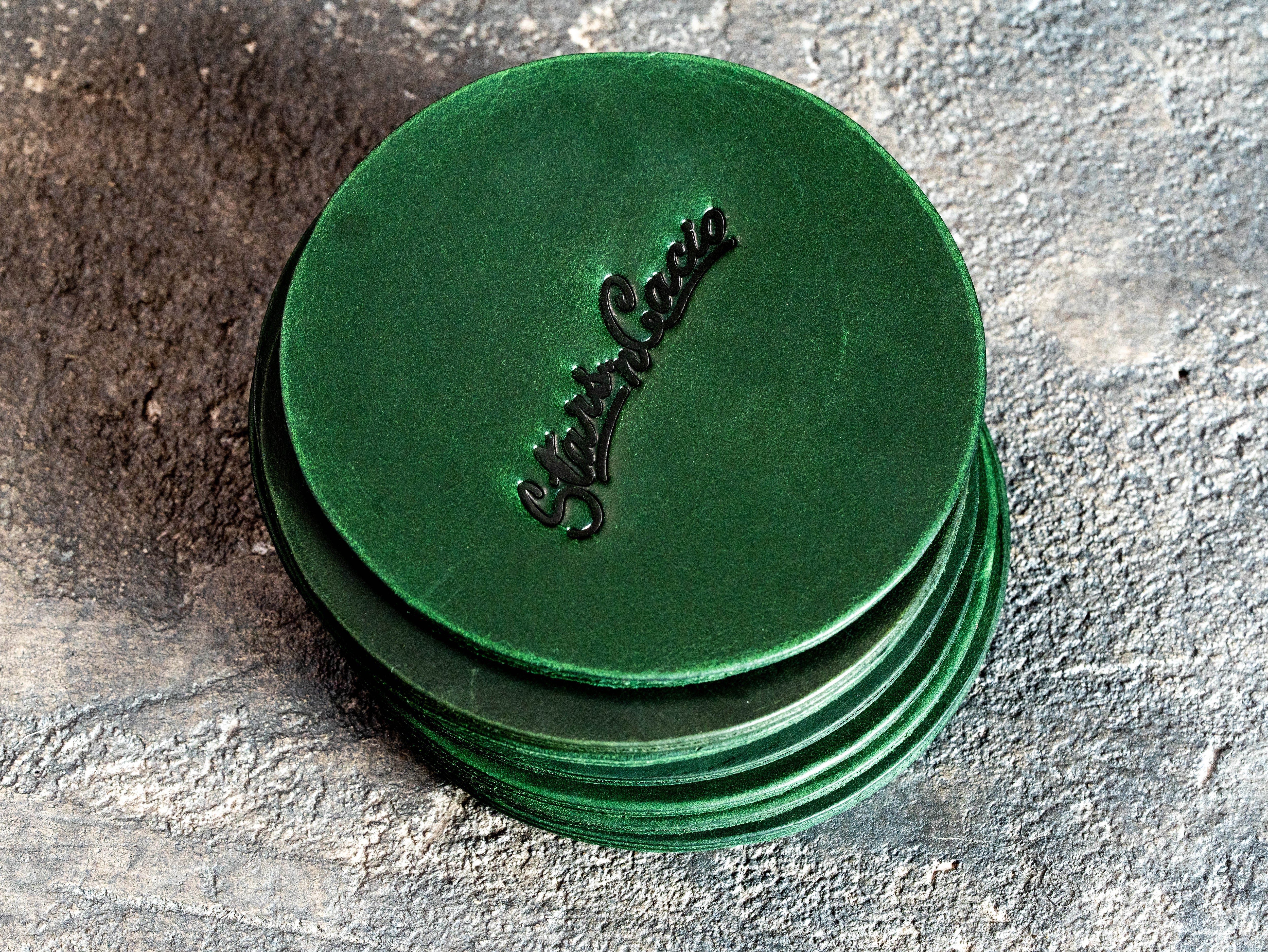 Stack of custom green Crazy Horse leather coasters with blind embossed Star in Cacio logo