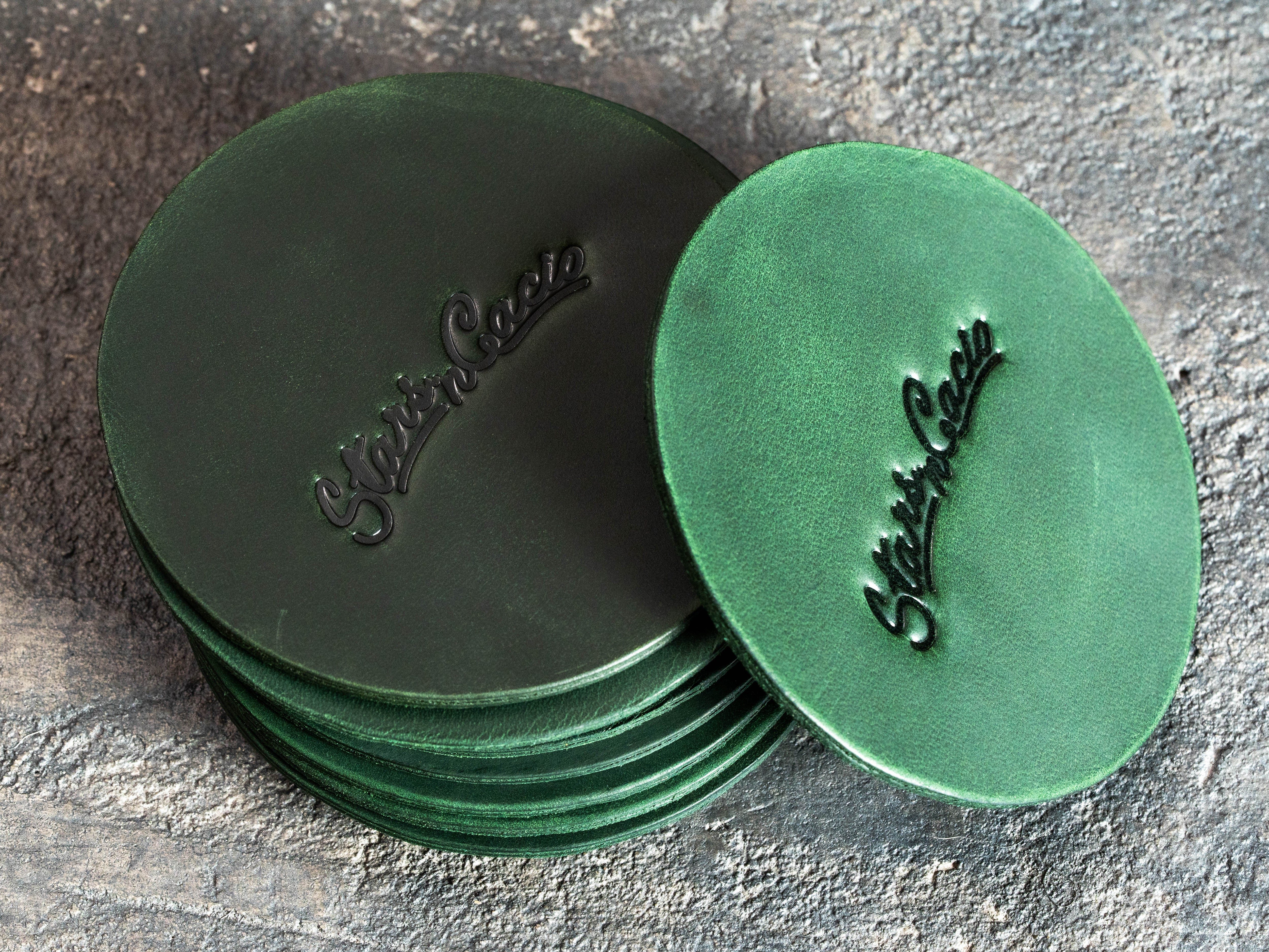 Round green leather logo coasters showing natural Crazy Horse texture and custom embossing