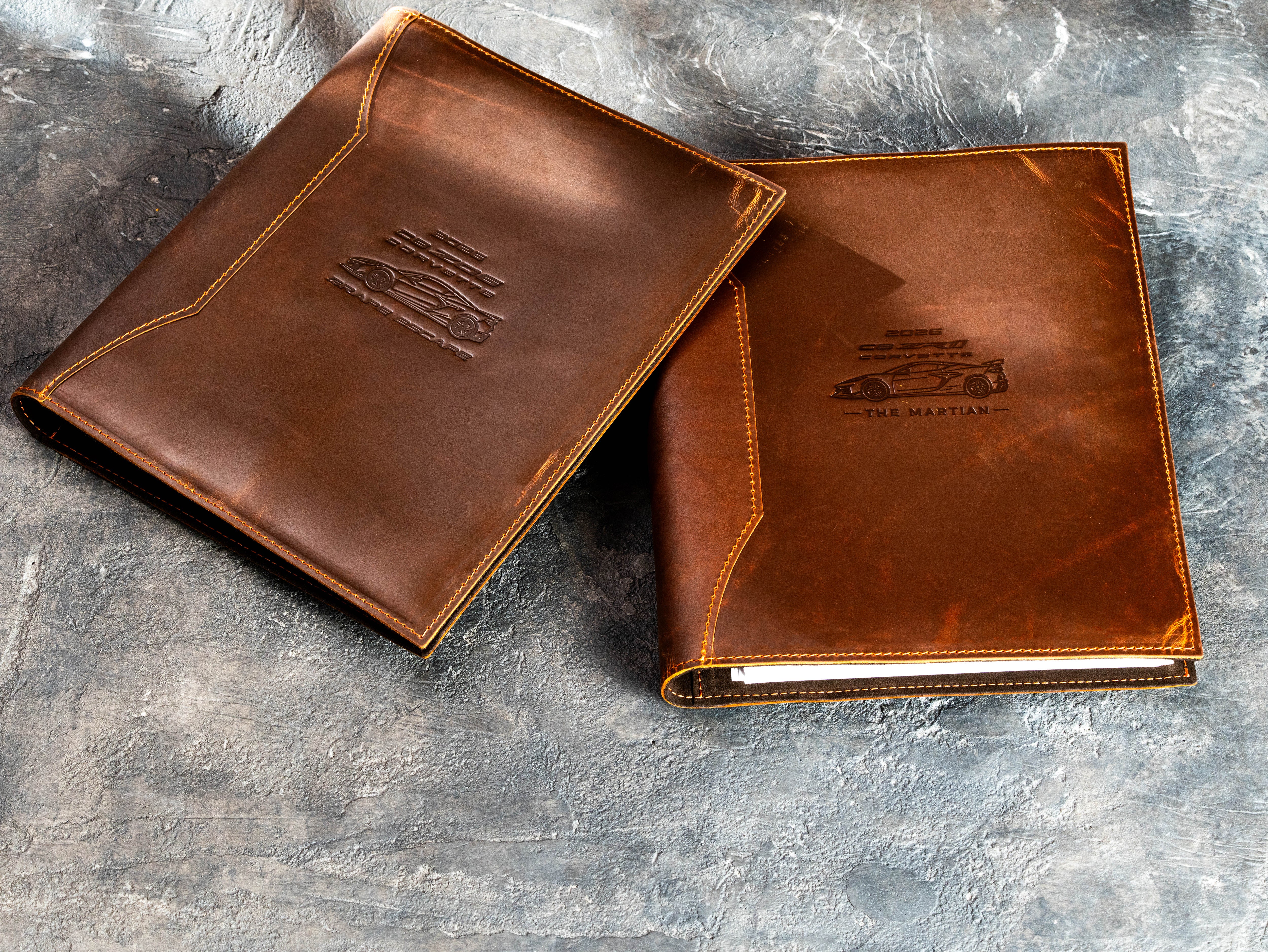 Pair of personalized leather car collector binders with custom vehicle illustrations and model text