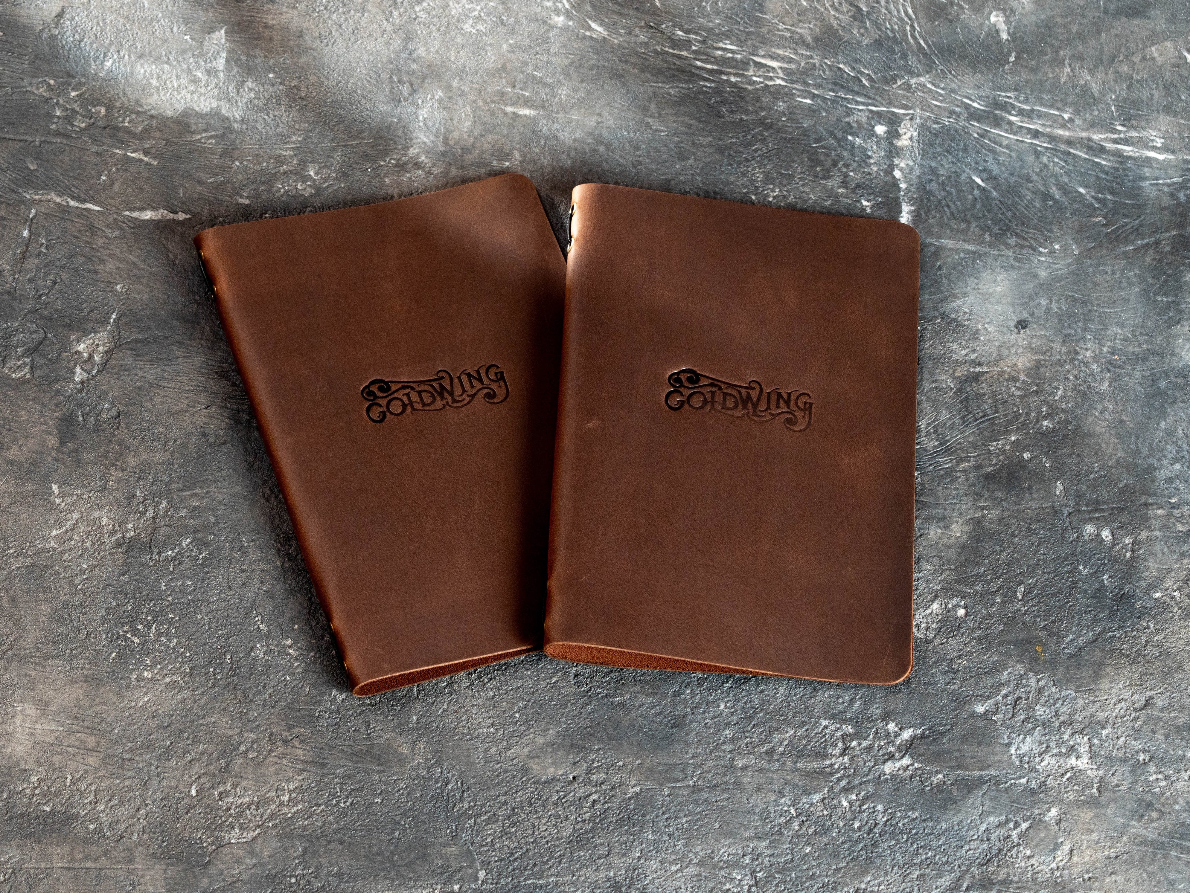 Two lightweight single-layer brown leather menu covers with custom embossed restaurant branding