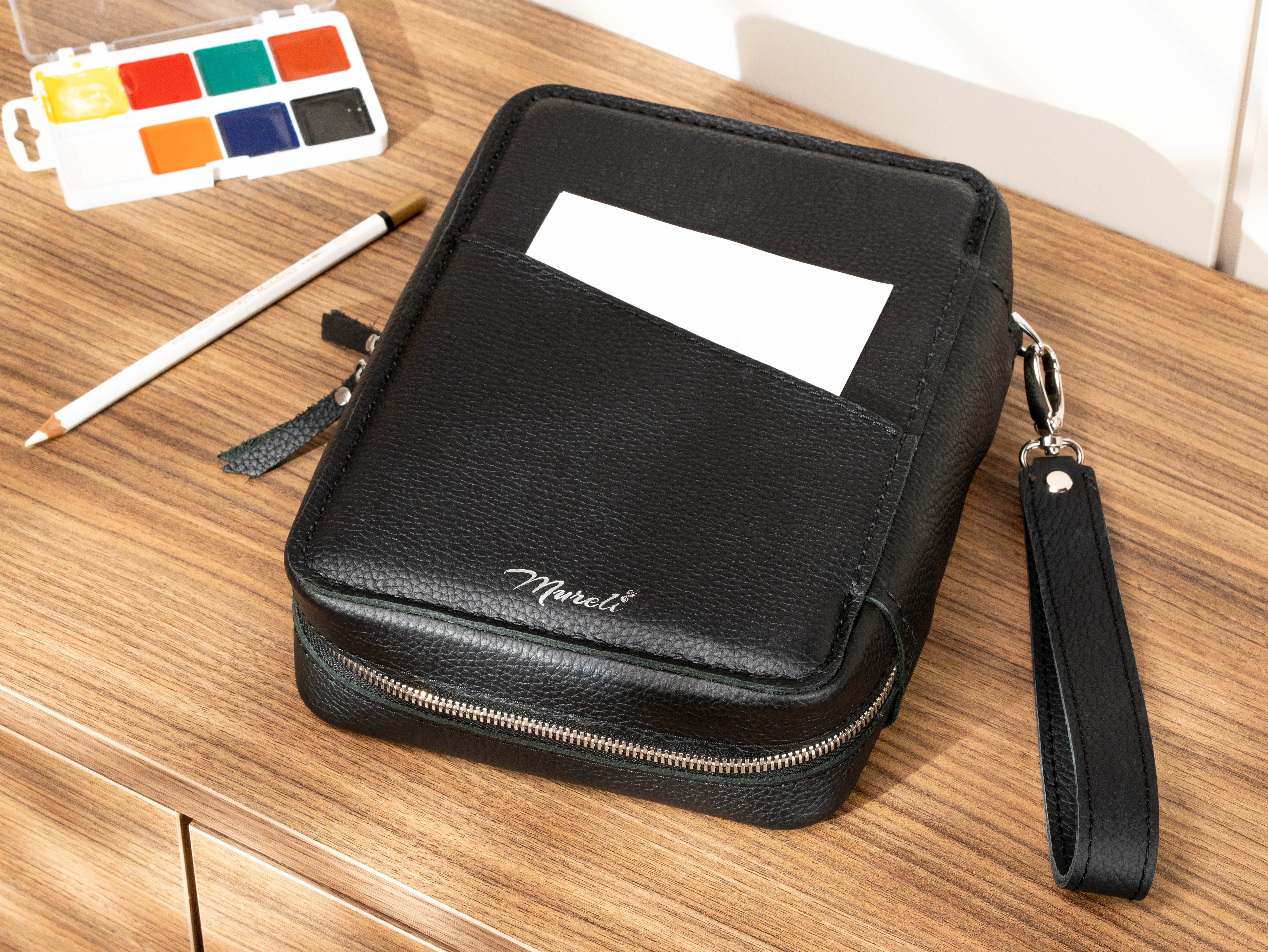 Back view of black leather artist organizer with exterior pocket for notes and detachable wrist strap