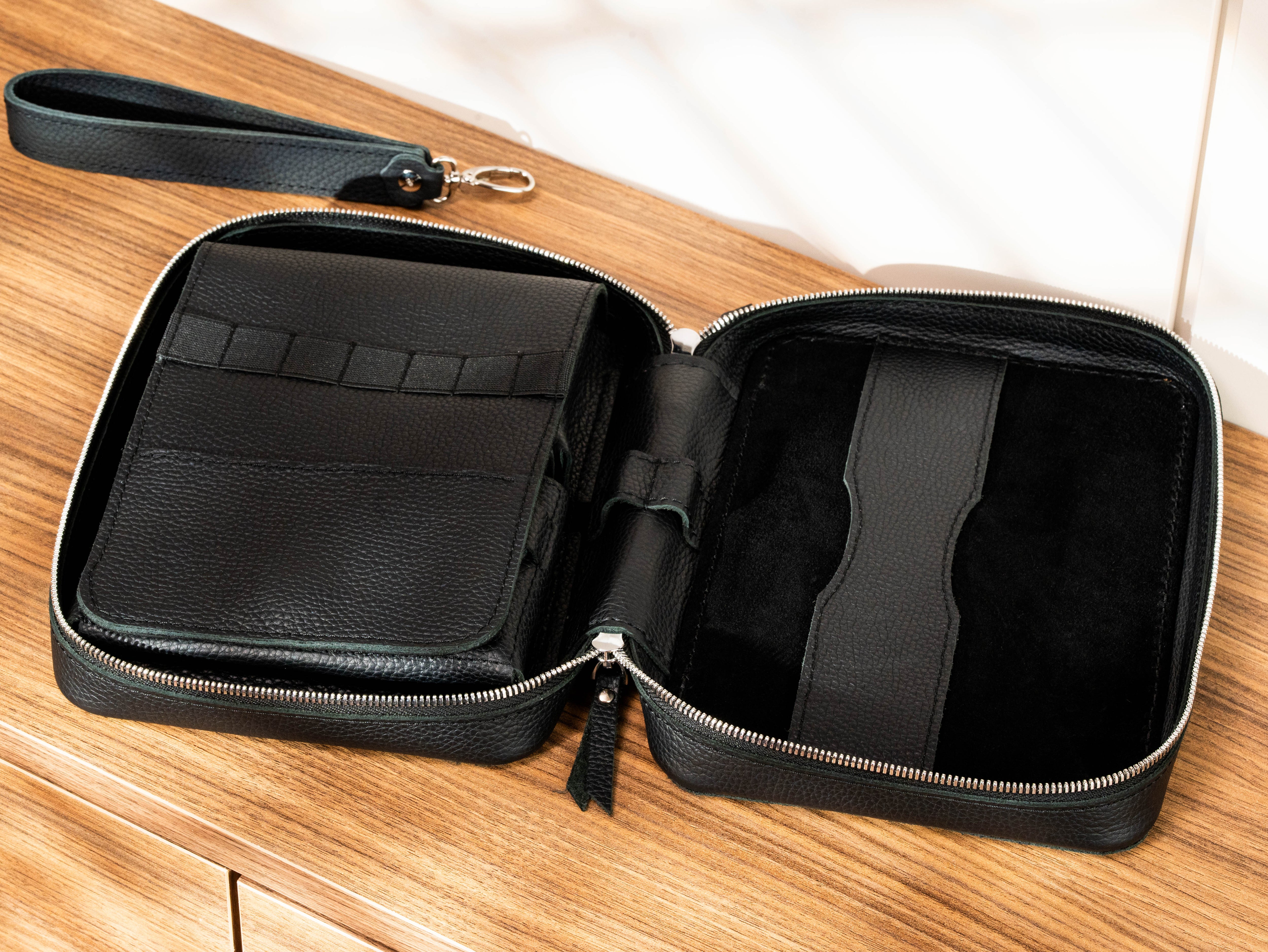 Open black leather artist organizer showing pencil loops, storage pockets, pen holders and A5 sketchbook compartment