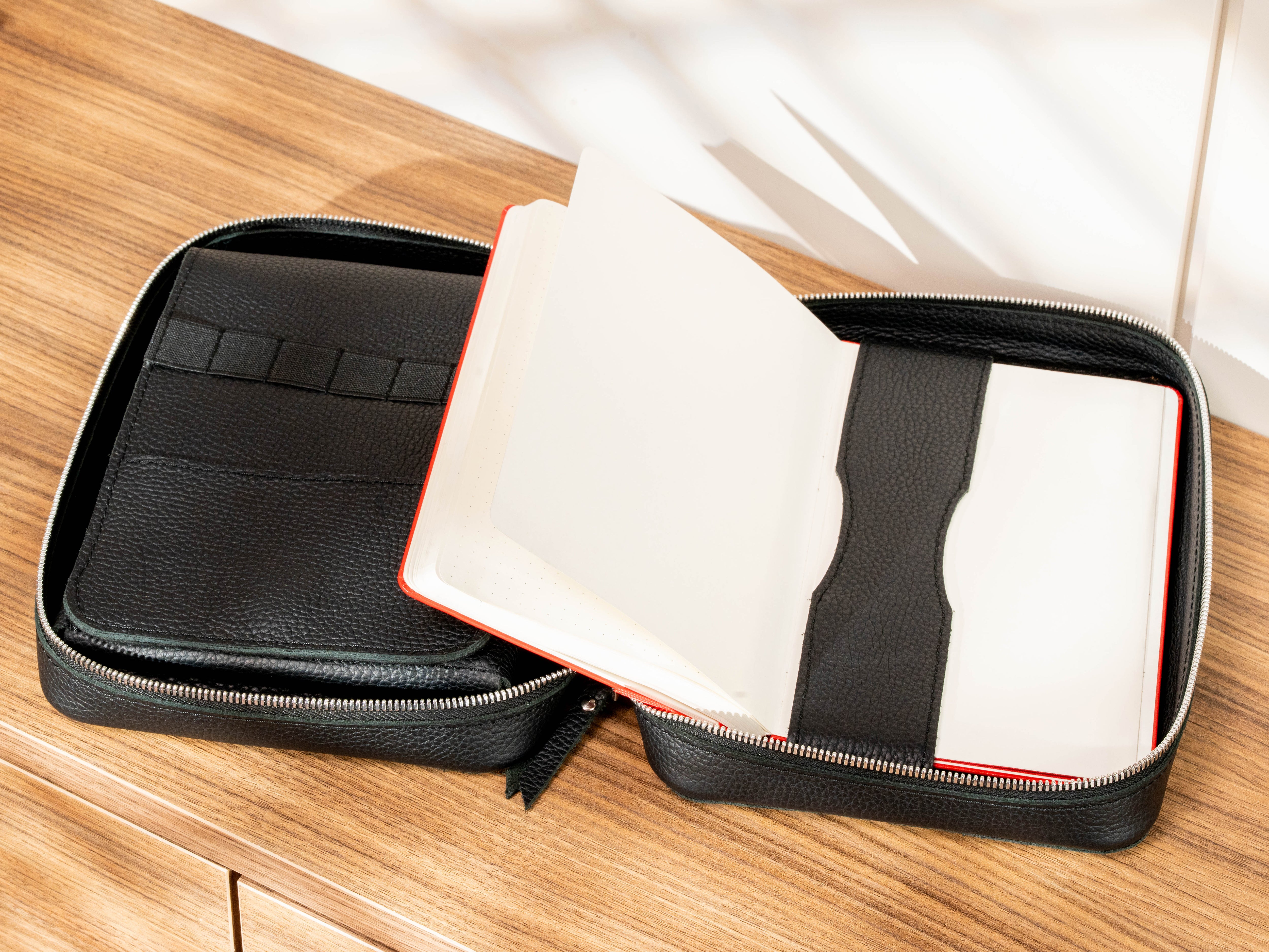 Black leather A5 sketchbook organizer with open notebook secured inside the travel art case