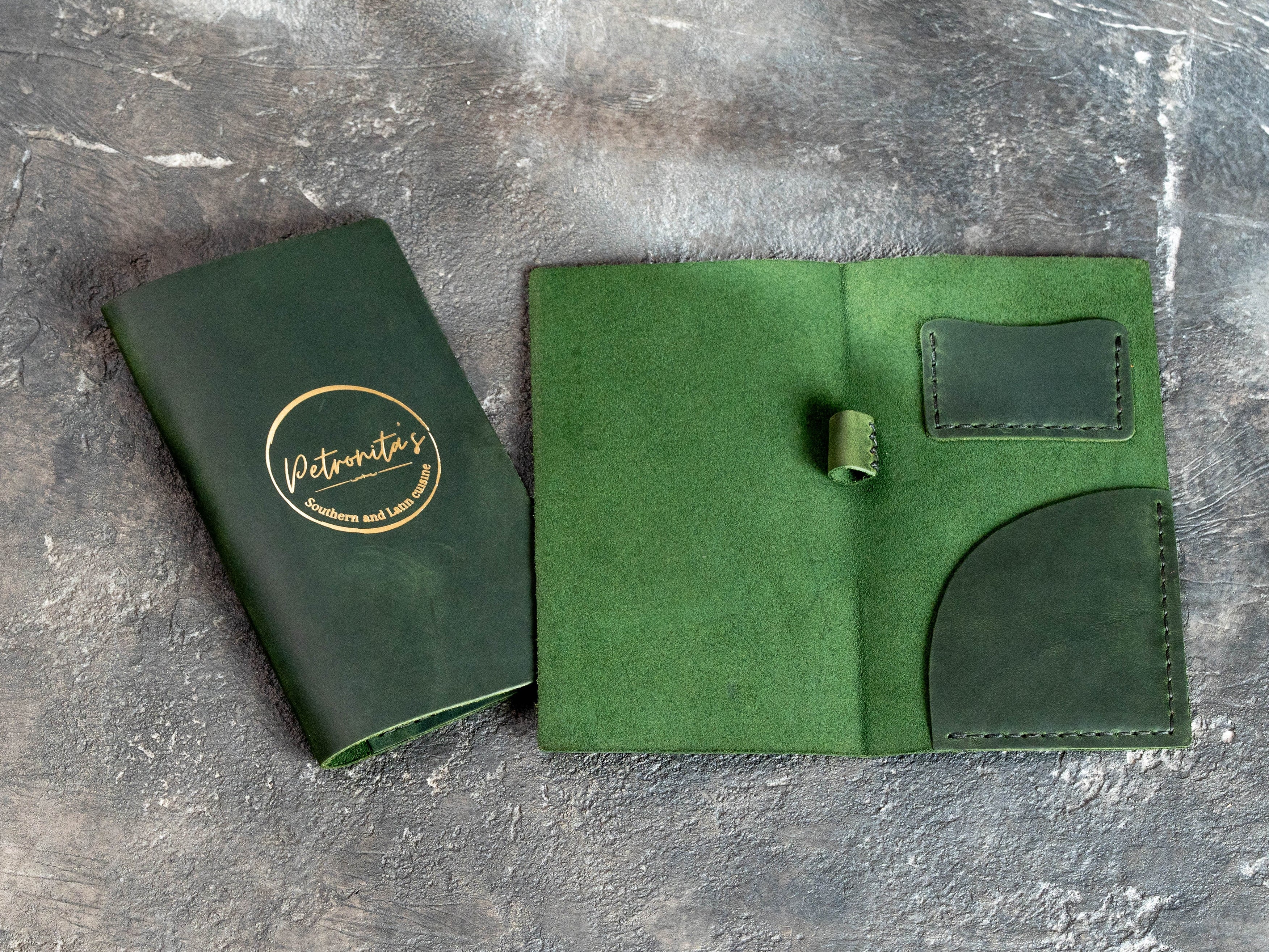Open green leather check presenter with receipt pocket, payment card pocket, and pen loop