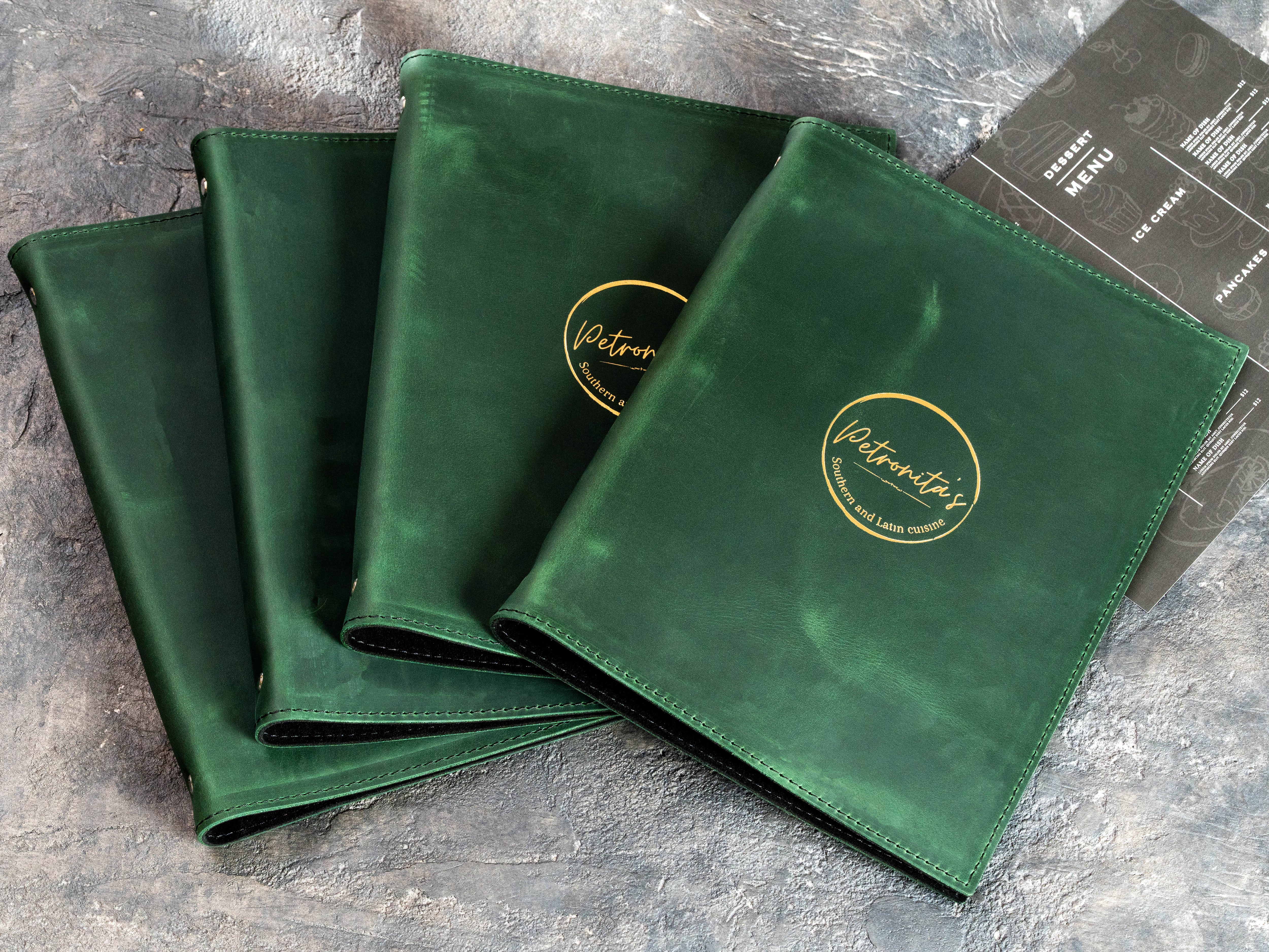 Set of custom green leather restaurant menu binders with gold foil Petronita’s logos