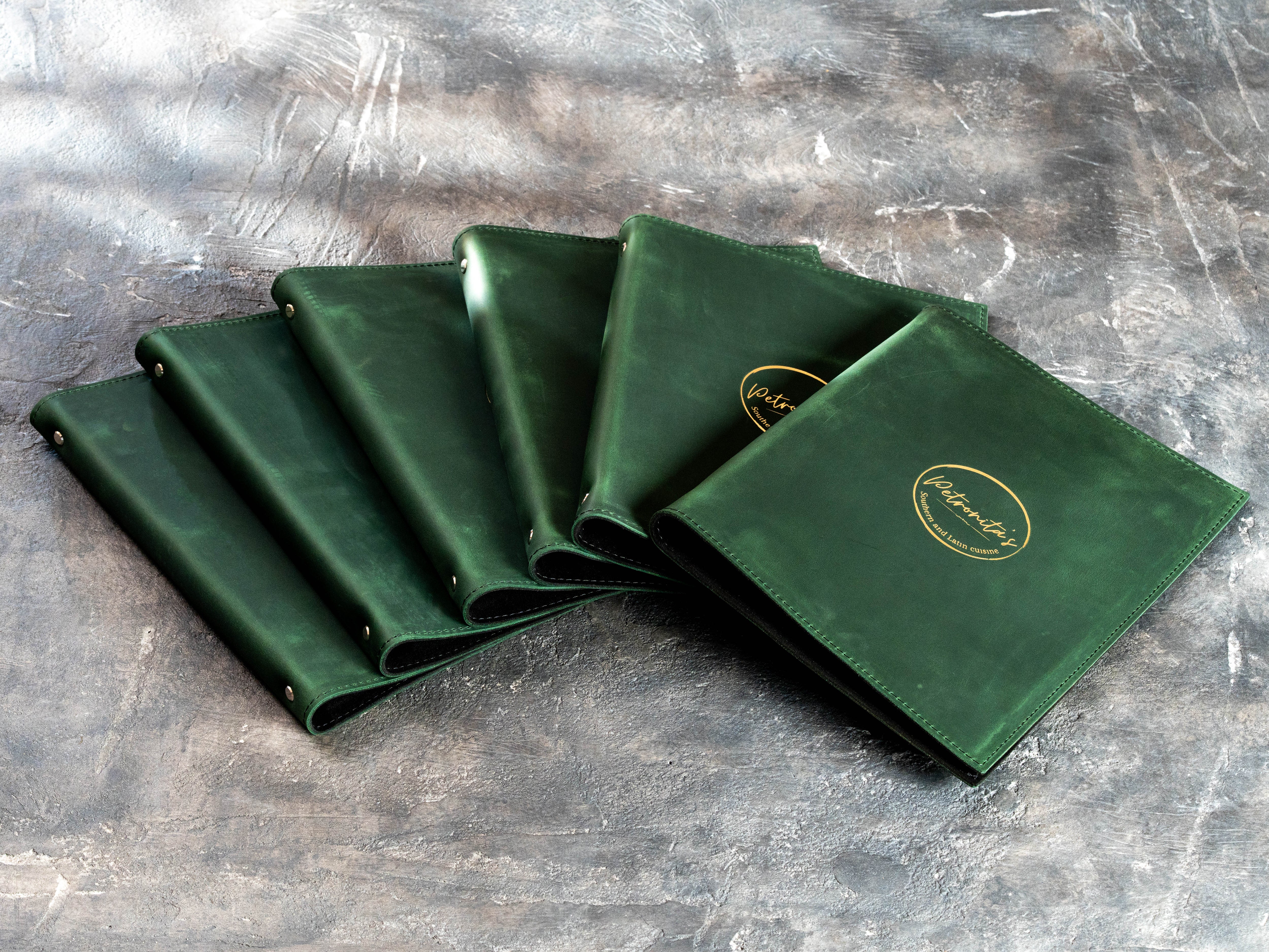 Custom green restaurant binder covers with stitched edges and gold foil logos