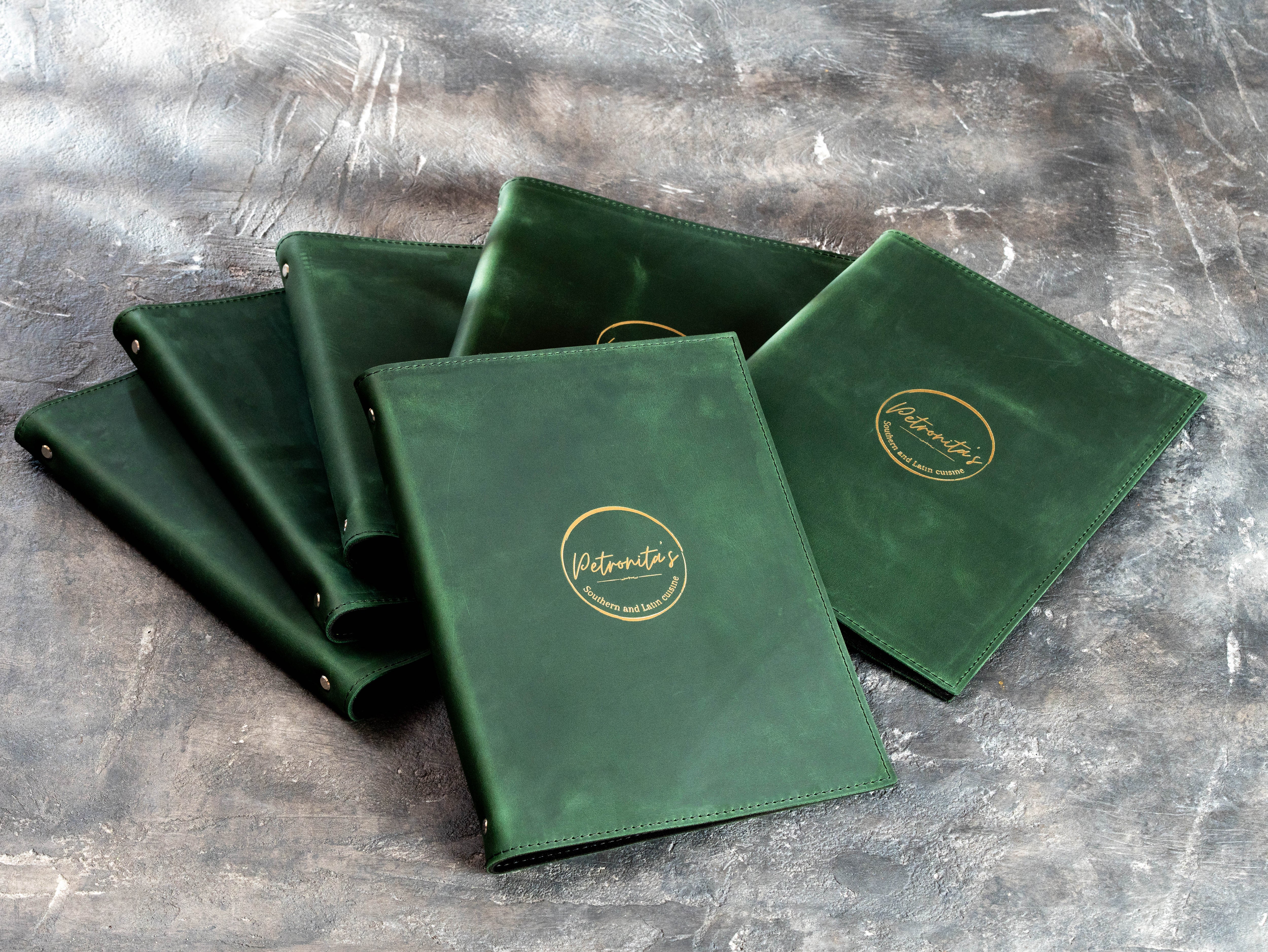 Set of green leather restaurant presentation folders with matching gold foil logos