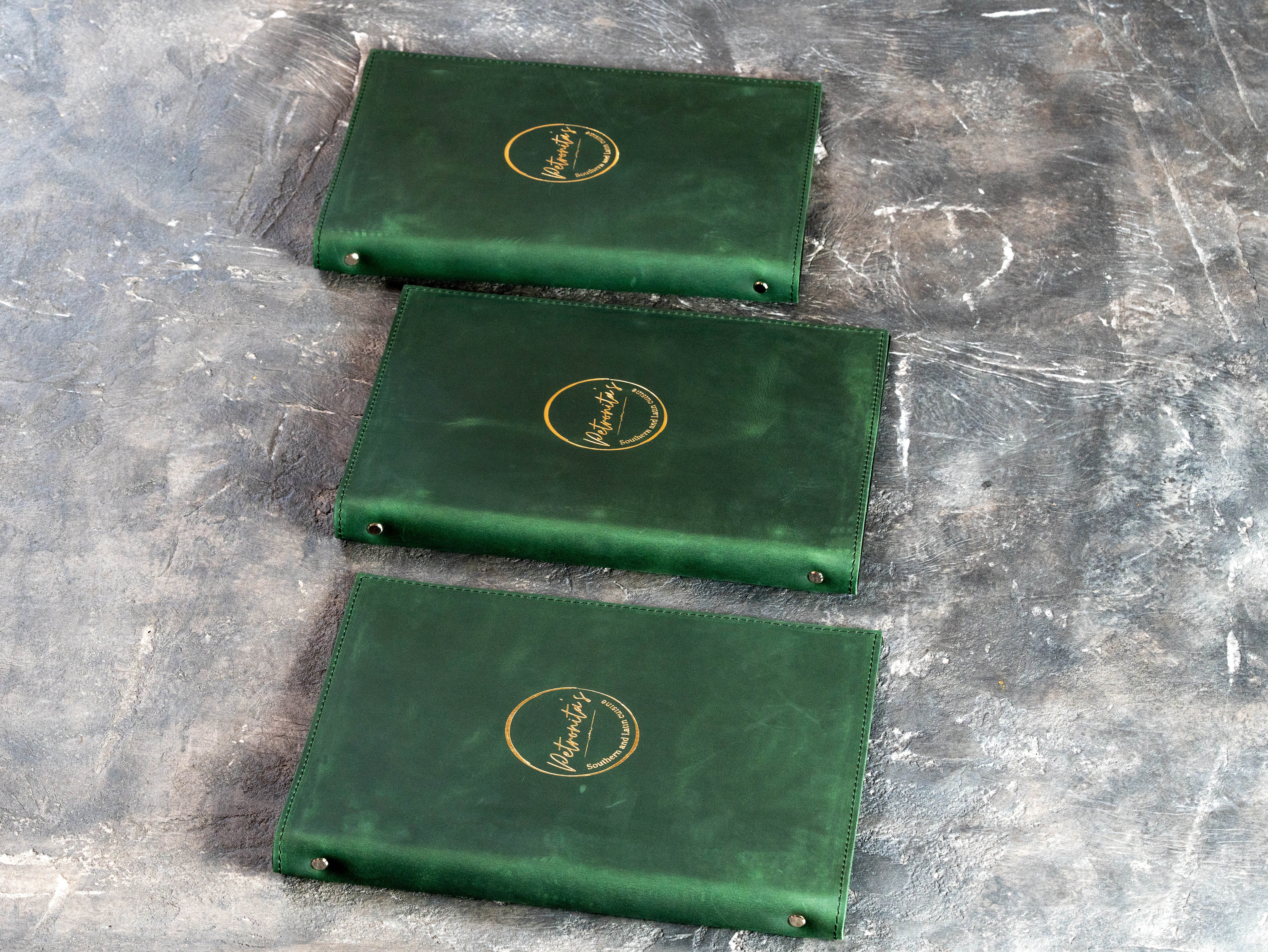 Custom branded menu folder with deep green leather exterior and contrasting black suede inside