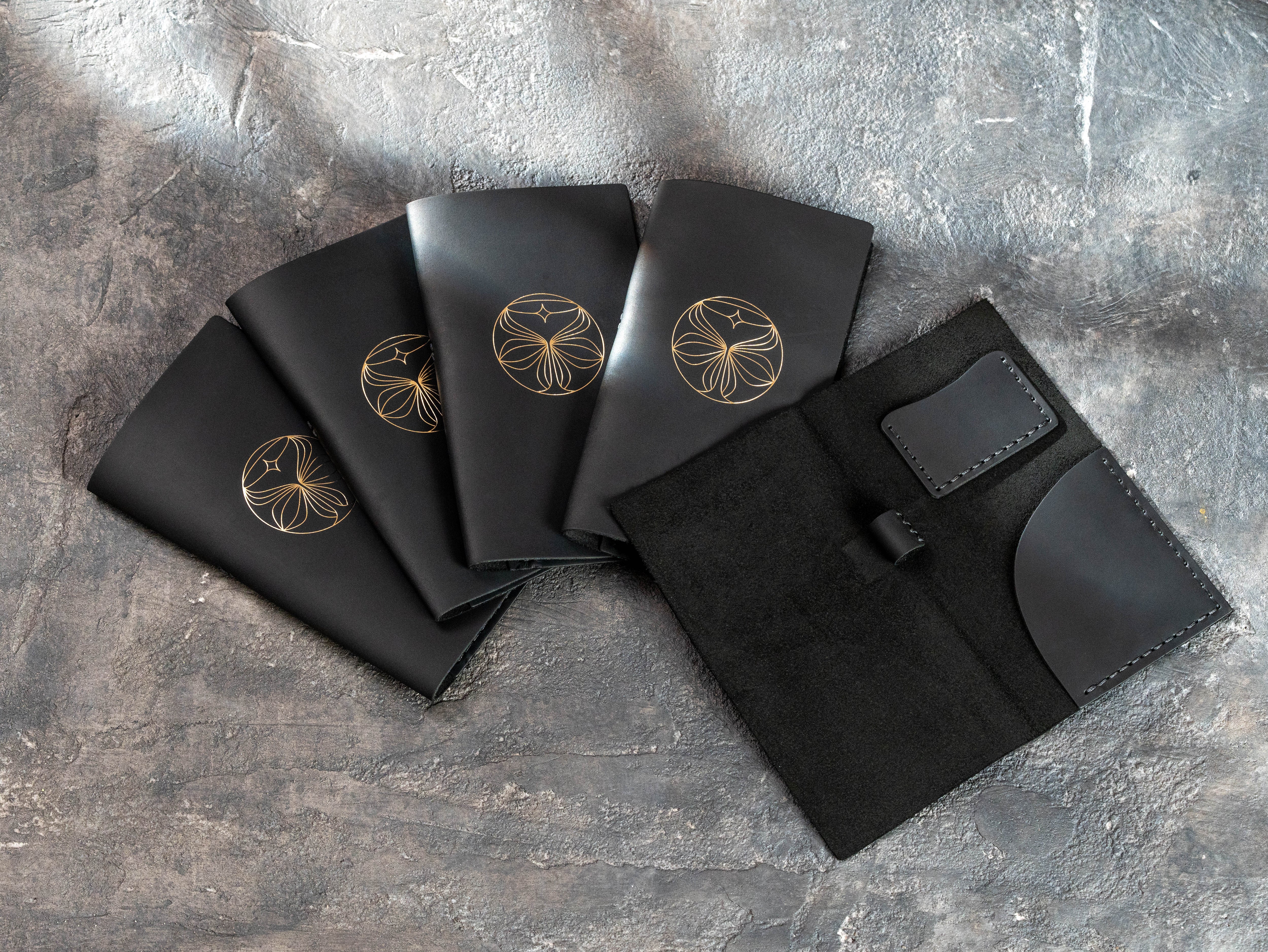 Black leather check presenters with gold foil logos and an open Design No. 5 interior featuring a receipt pocket, card pocket, and pen loop