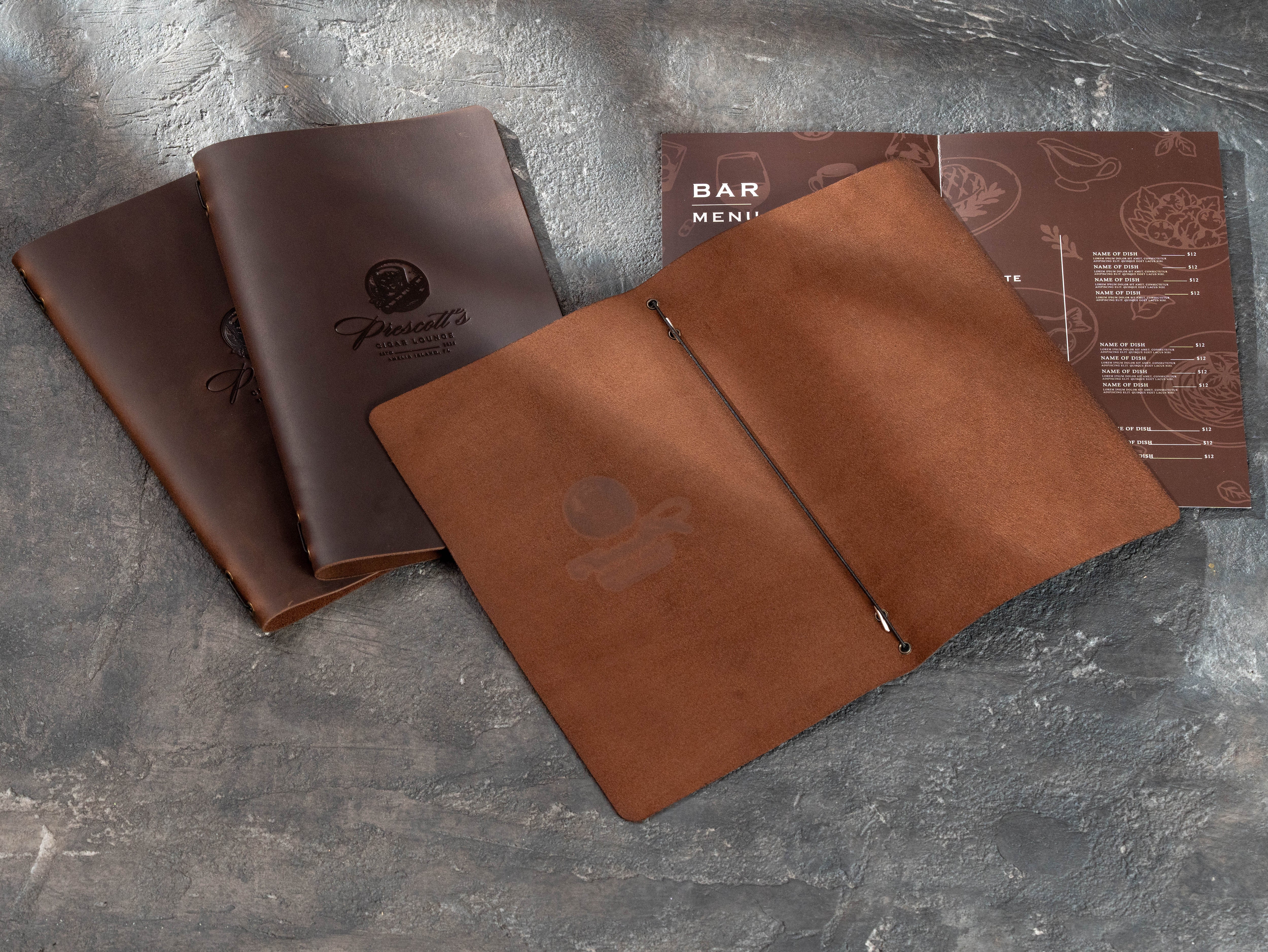 Open brown leather bar menu cover with elastic binding holding a folded drinks and food menu