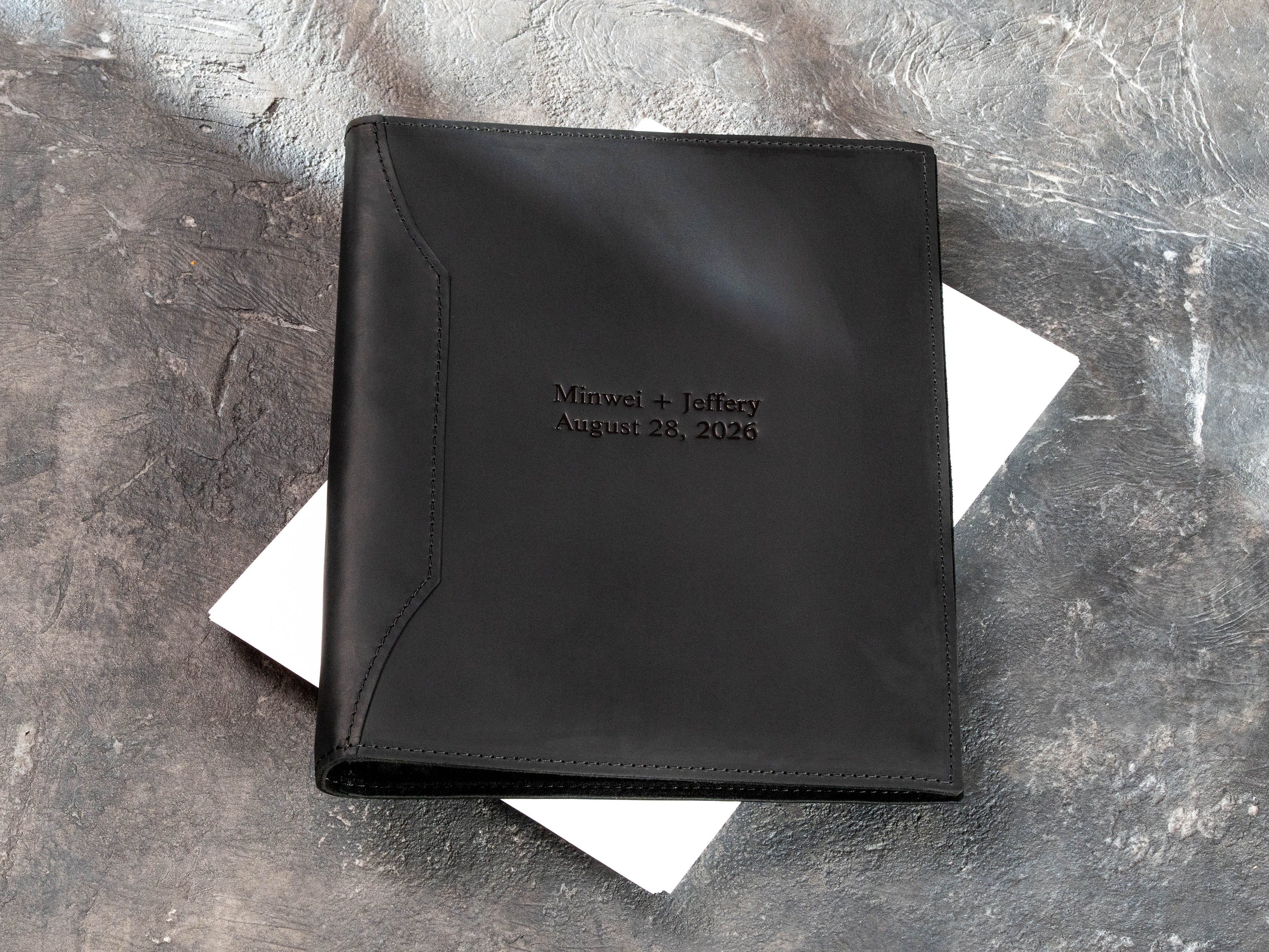 Closed black leather wedding binder personalized with Minwei and Jeffery names and August 28, 2026 date