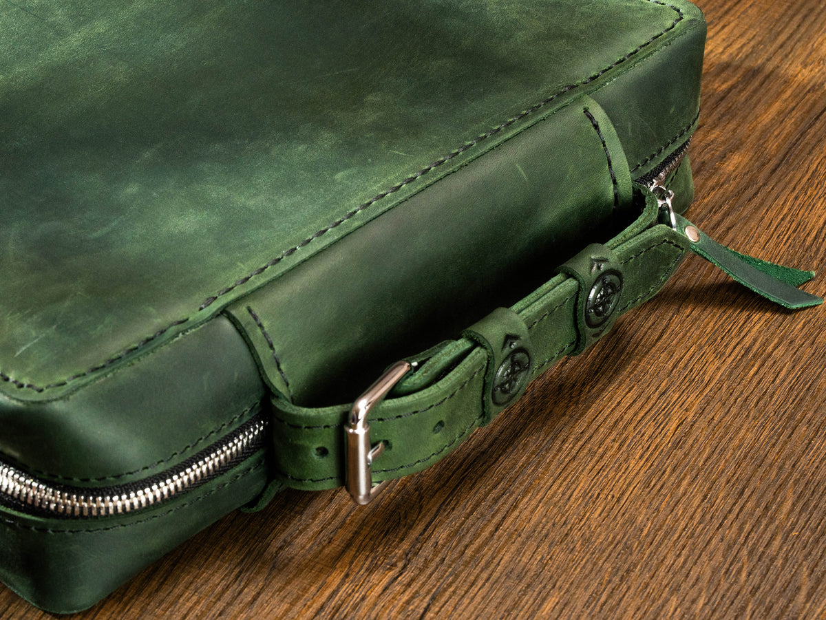 Forest Green leather outdoor travel organizer close-up with belt-style handle, compass details and zip-around closure