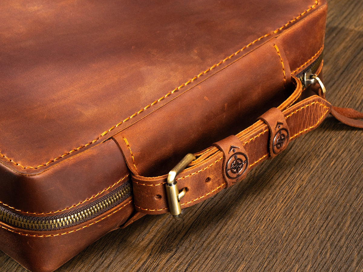 Copper Brown leather travel organizer case close-up with belt-style handle, compass details and zip-around closure