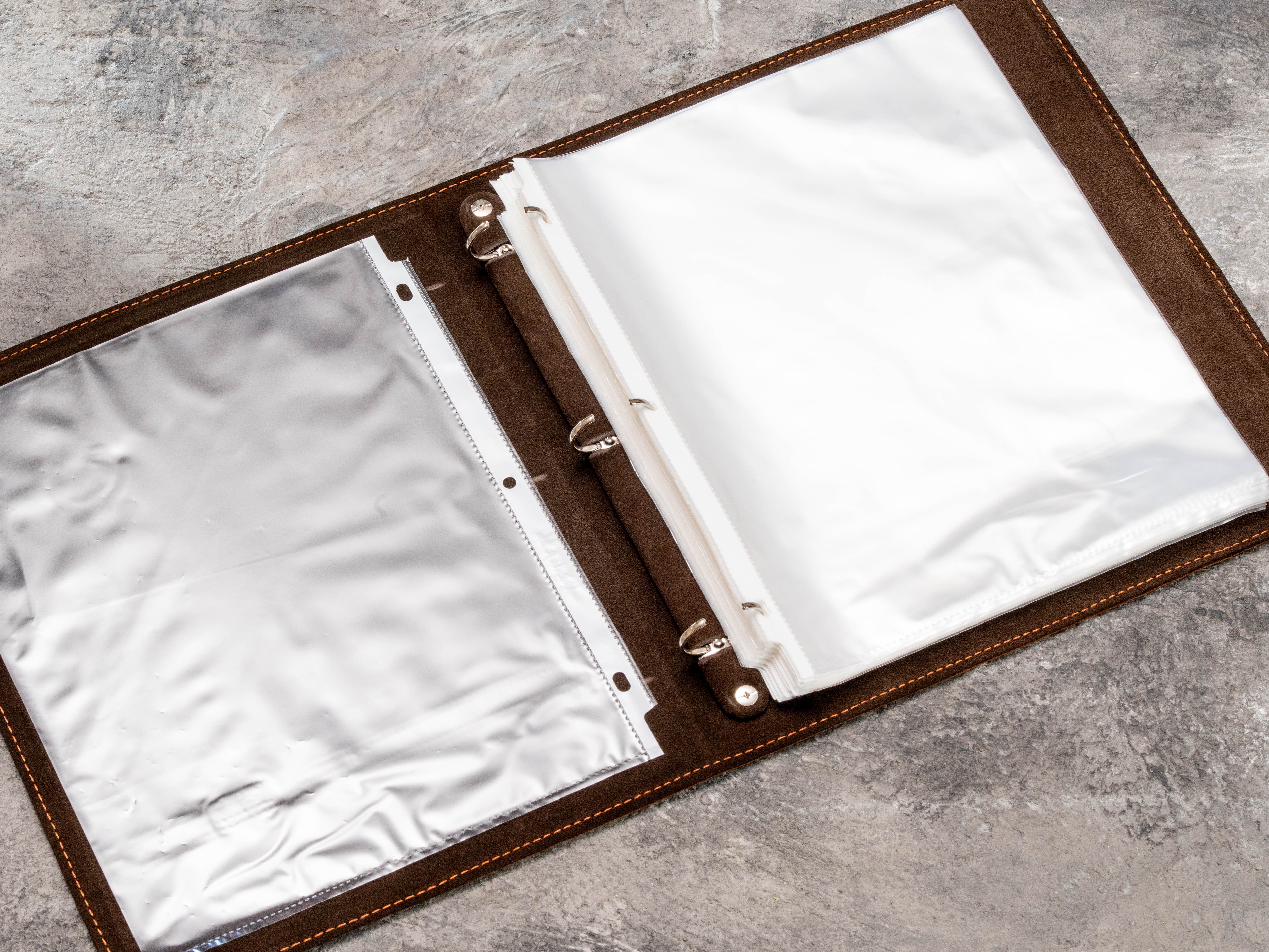 Open personalized leather construction binder showing removable plastic page protectors for project documents