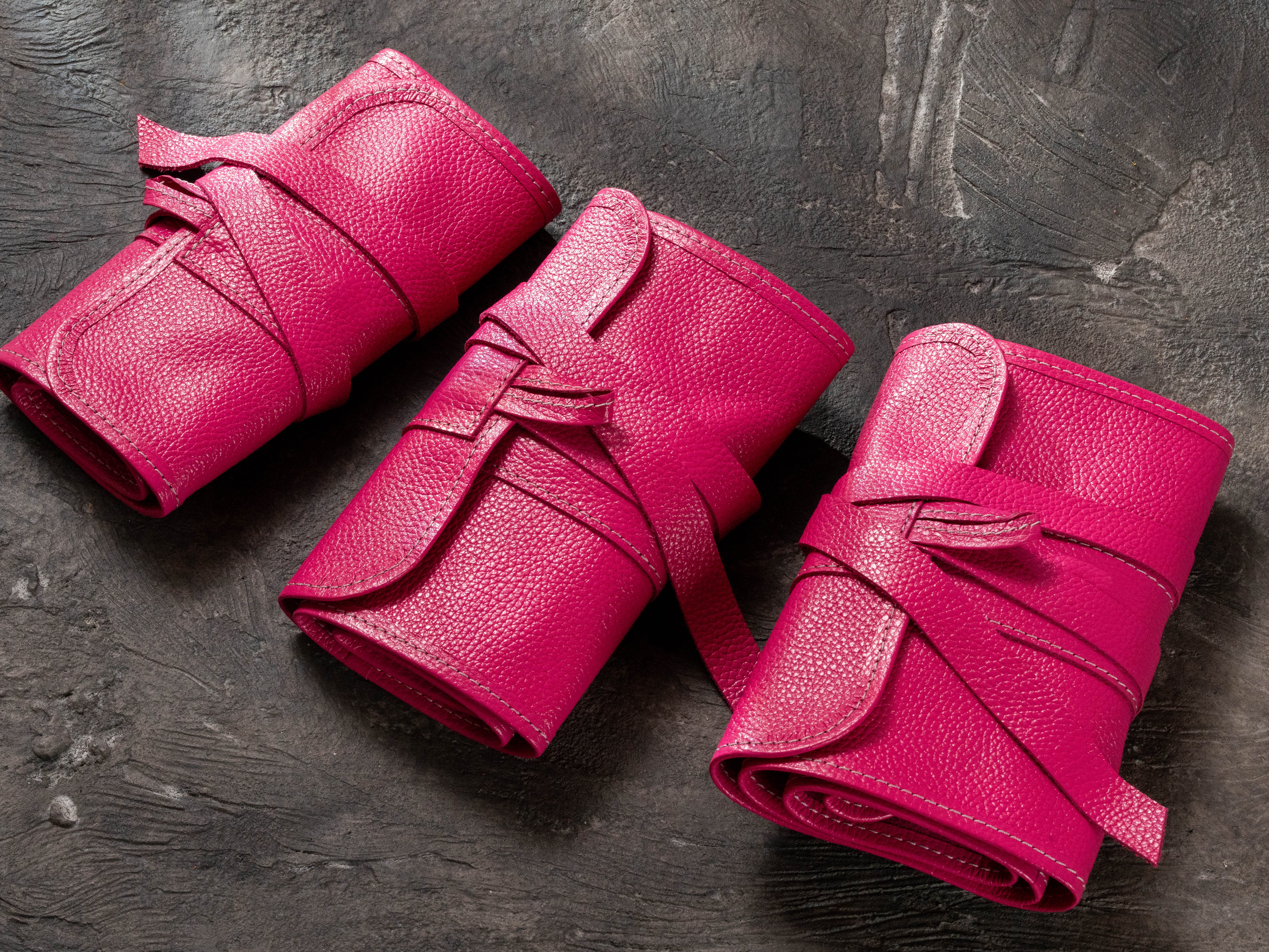 Set of three bright pink leather pencil rolls in Small, Medium and Large sizes for artists