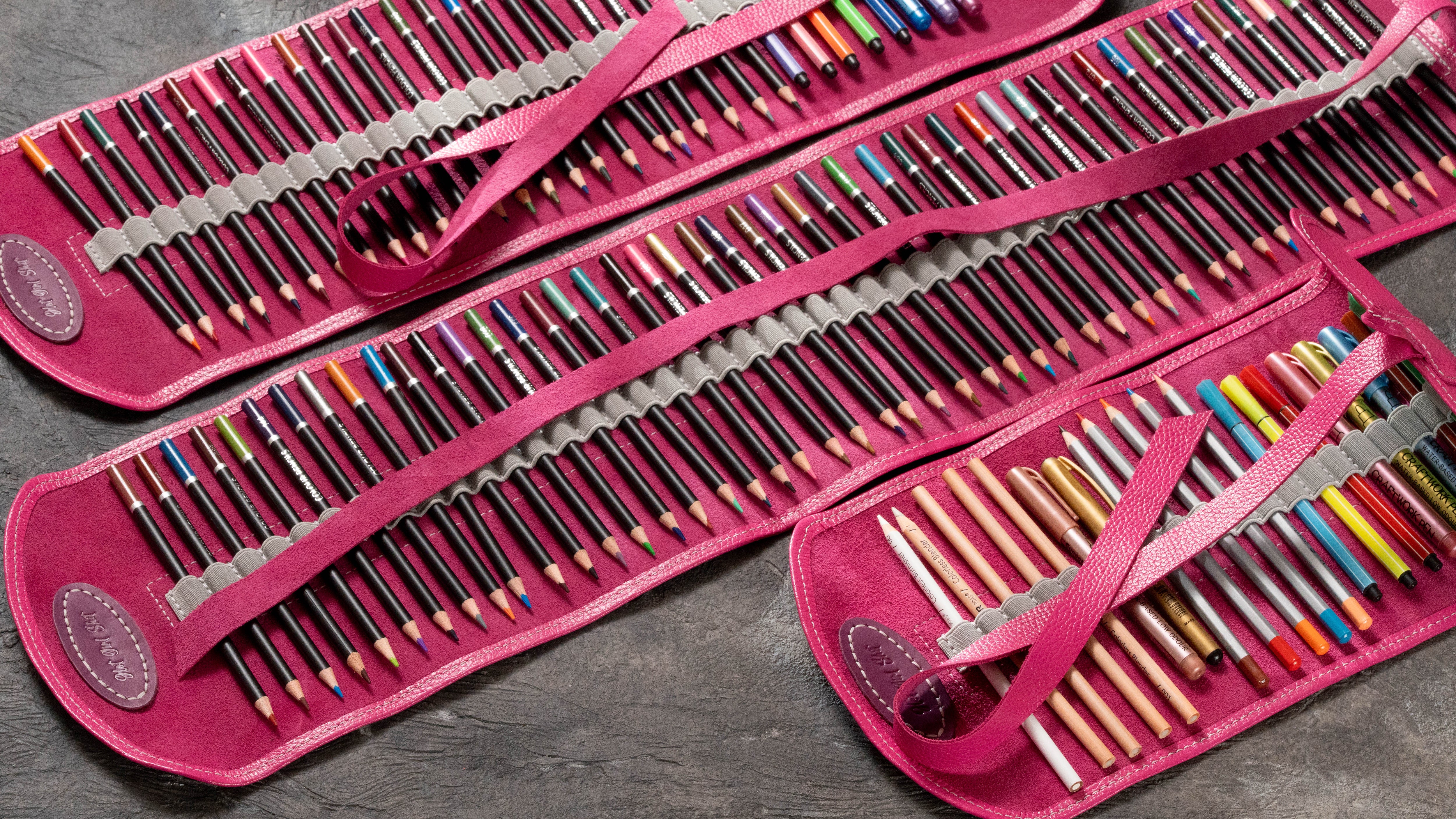 Three-size pink leather pencil roll set filled with colored pencils, markers and art supplies