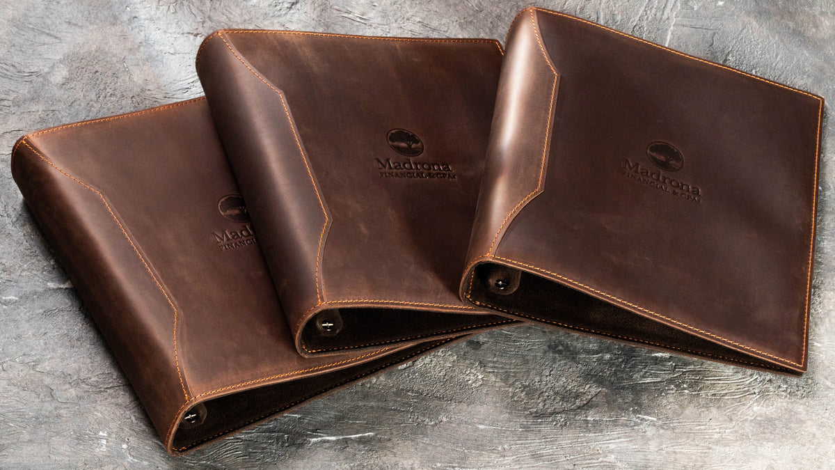 Brown leather corporate D-ring binders with Madrona Financial & CPAs logo for financial advisor team