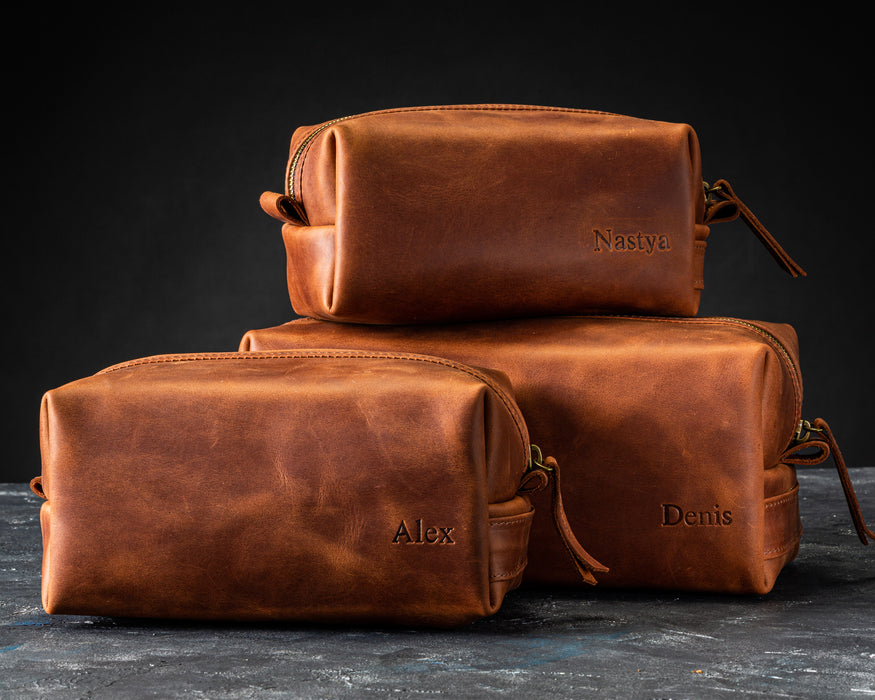 Woman holding dark brown leather toiletry bag with engraved name Almaz