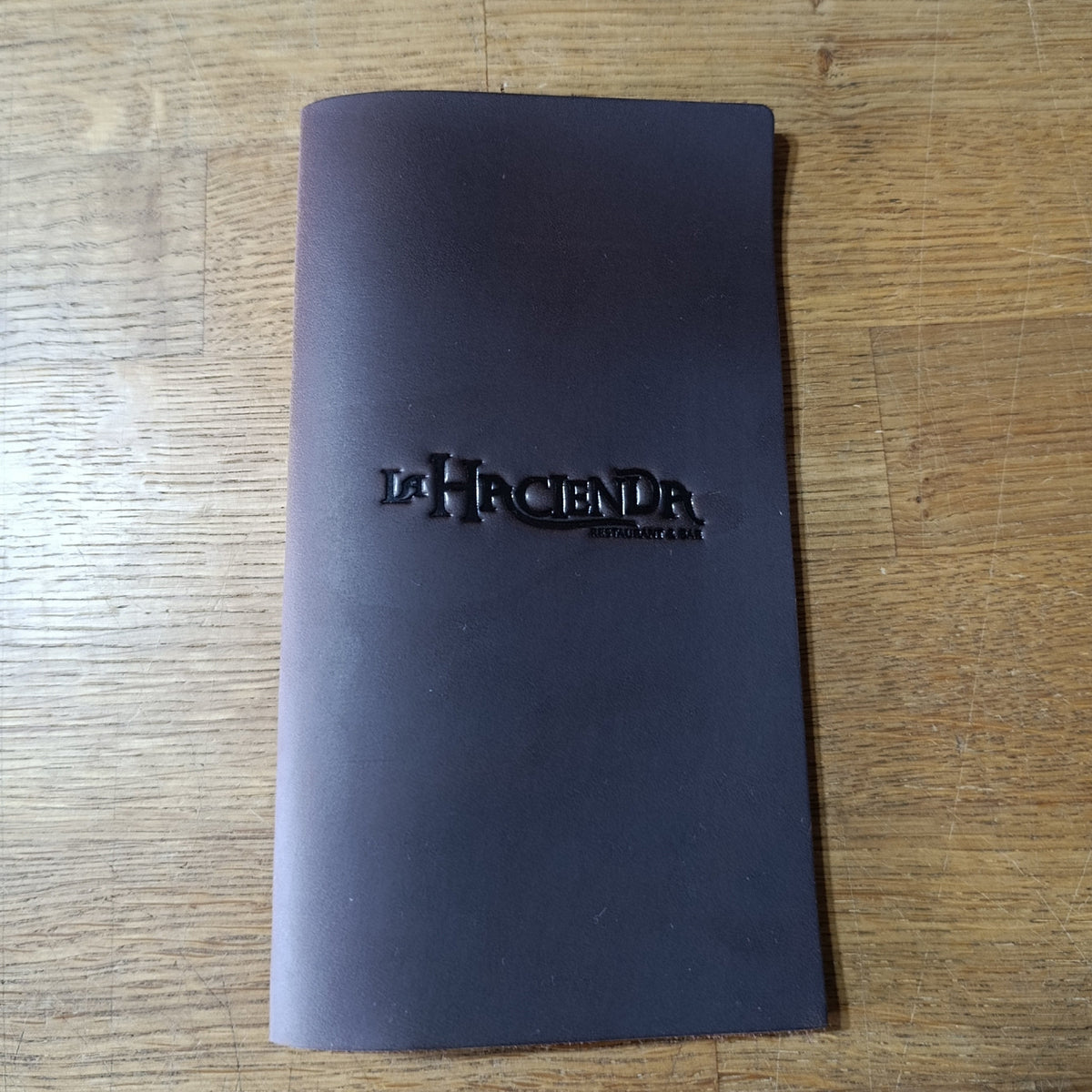 Custom leather check presenter with La Hacienda restaurant logo – approved sample for 150-piece bulk order
