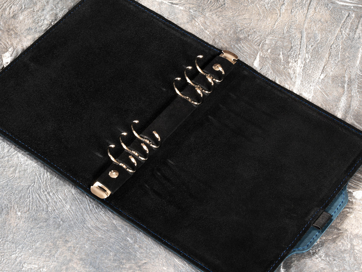 Open Deep Blue leather notebook showing six-ring mechanism and black suede interior
