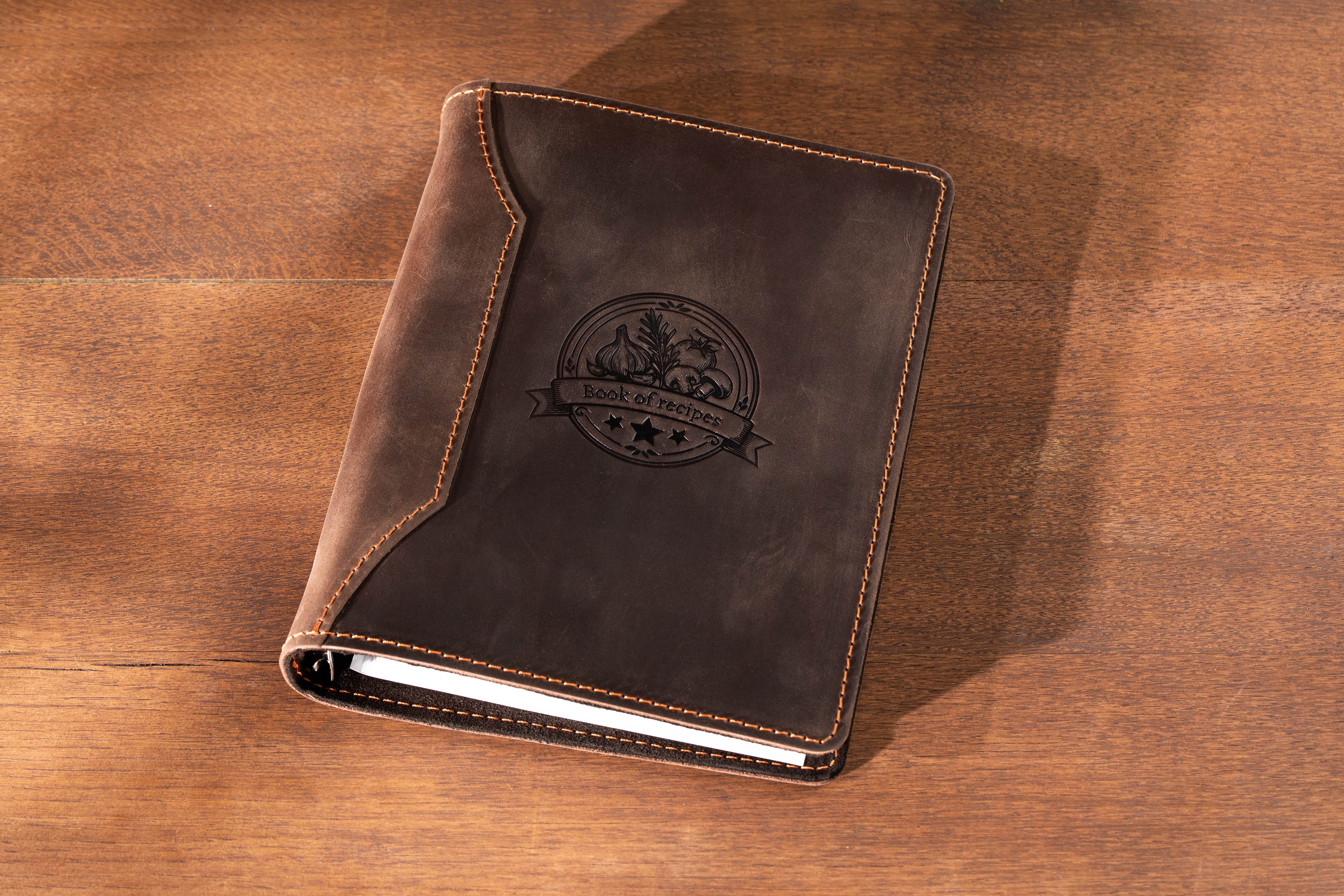 Brown leather notebook with a logo on a wooden surface
