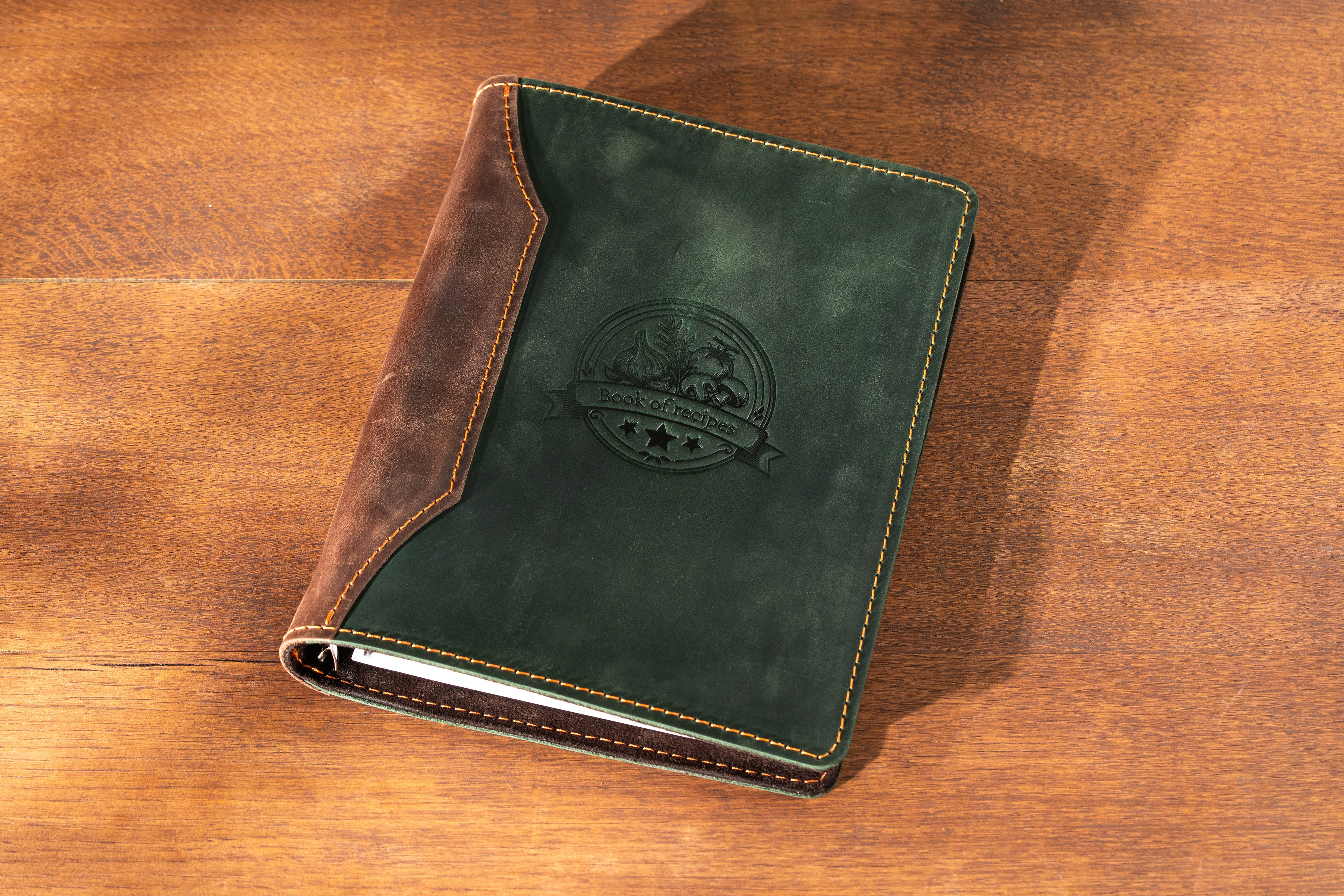 Green leather notebook with brown edges on a wooden surface