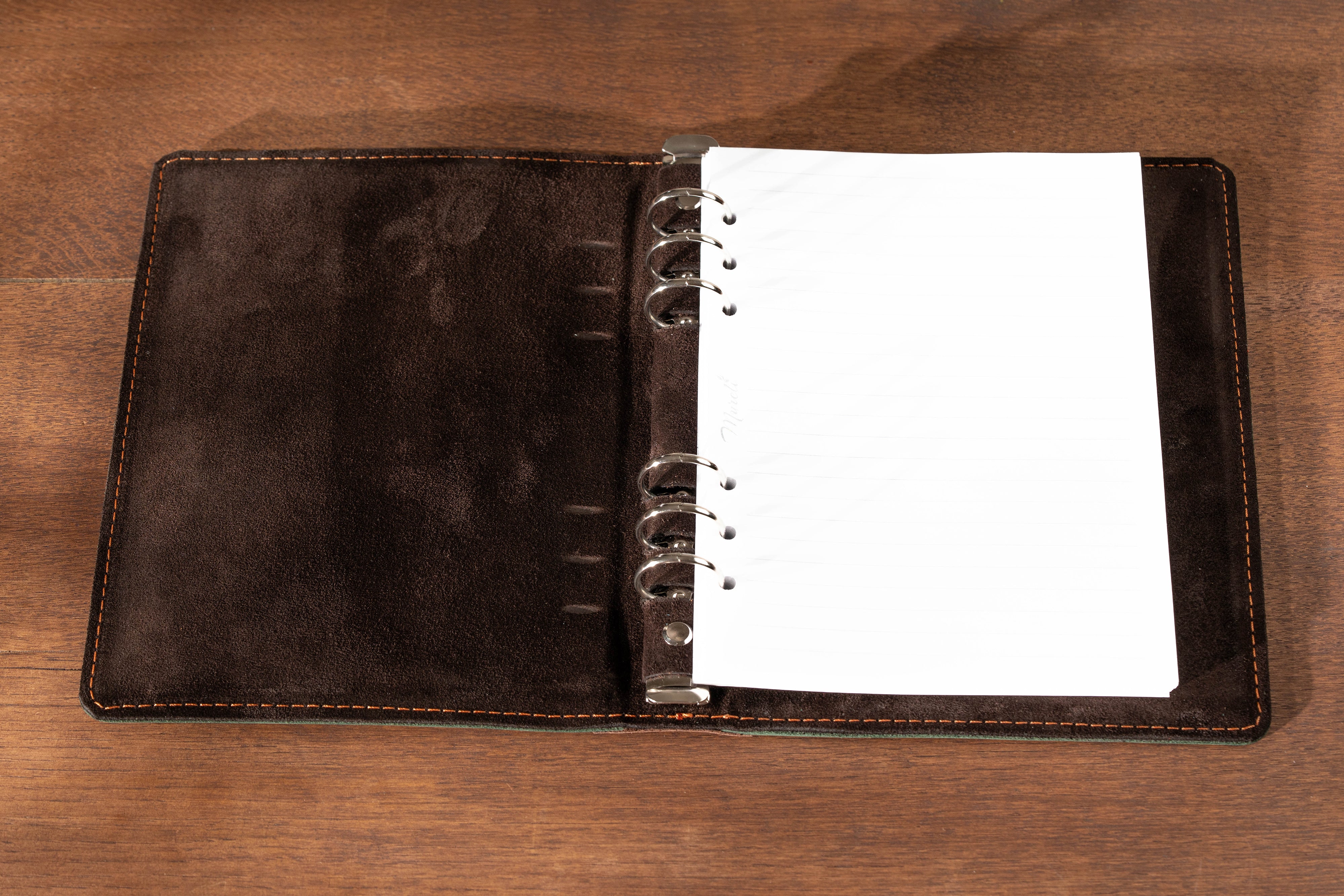 Brown leather notebook with white pages on a wooden surface