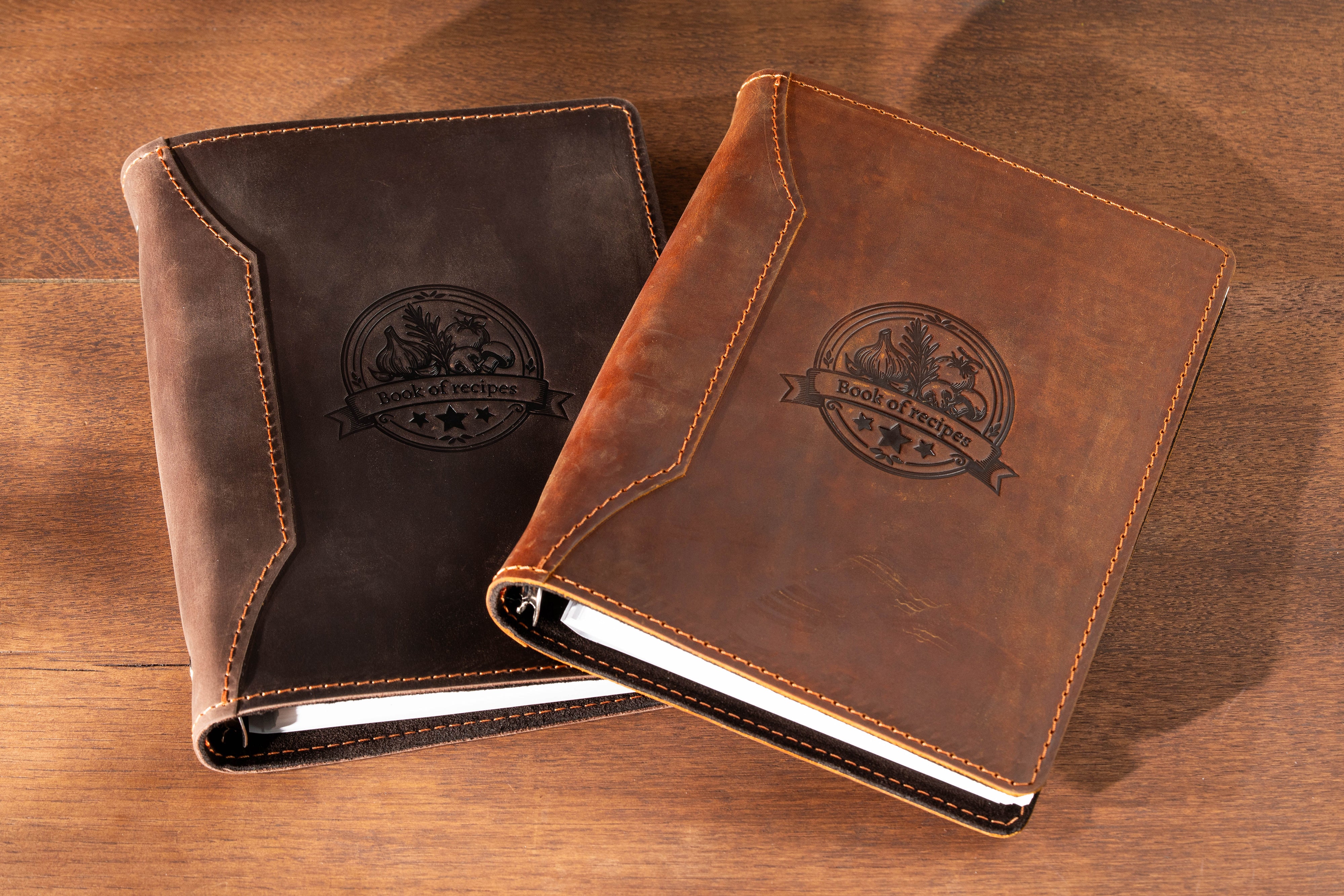 Two leather-bound brown notebooks with embossed logos