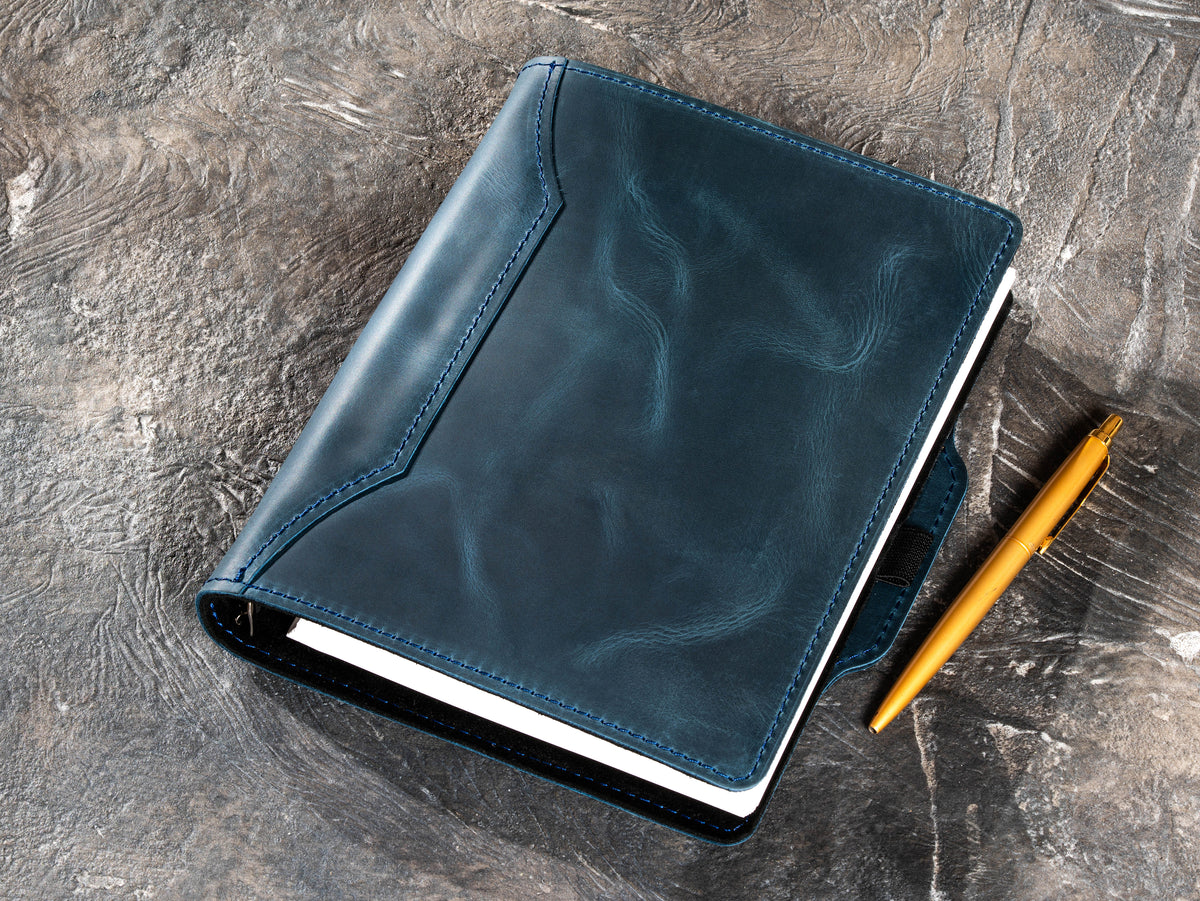 Deep Blue leather notebook with gold pen beside the refillable cover