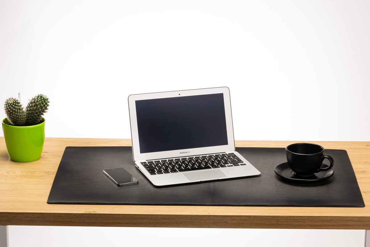 Gray 3–4 mm thick leather desk mat with hand-darkened edges on modern office desk with laptop