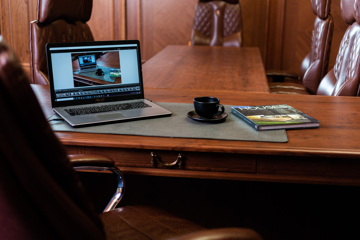 Gray leather desk mat for executive office and conference table with laptop and meeting room chairs