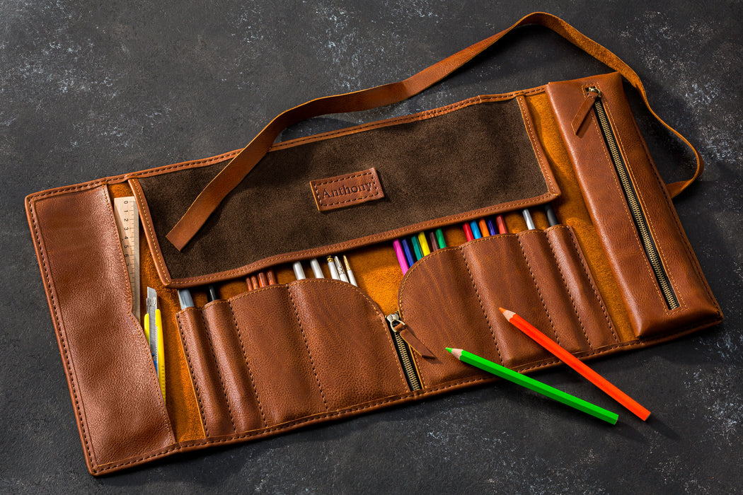 Brown leather pencil case with colorful pencils on a dark surface