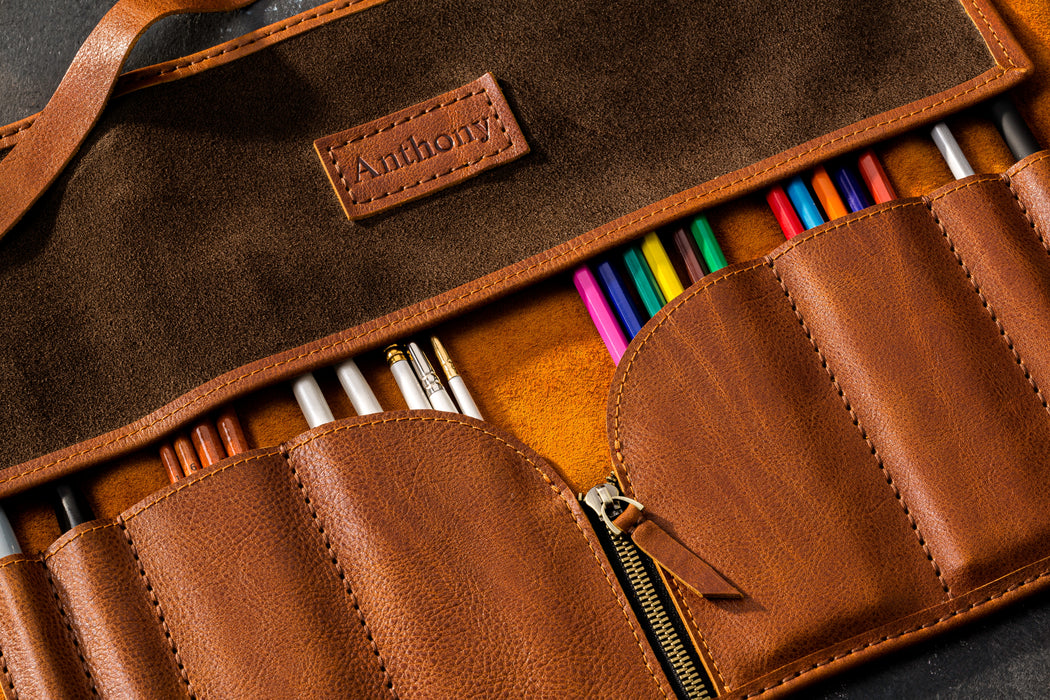Brown leather pencil case with  branding, containing colored pencils.