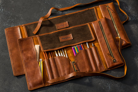 Two personalized leather artist roll organizers in Cognac Brown with brushes, pencils, and tools inside — handcrafted and labeled