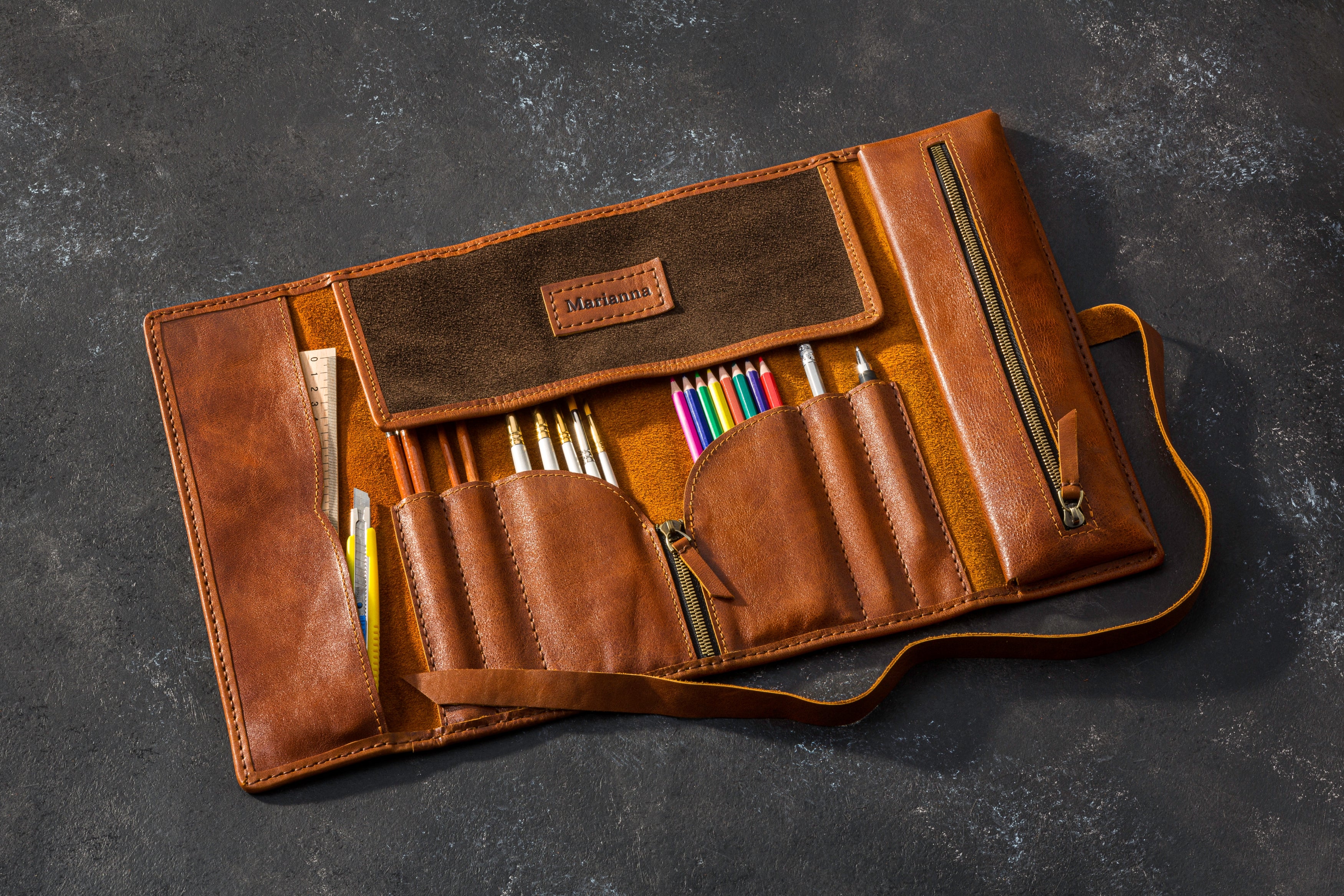Brown leather pencil case with colorful pencils on a dark gray background standard size