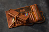 Two Brown leather pencil roll with colorful pencils on a dark surface