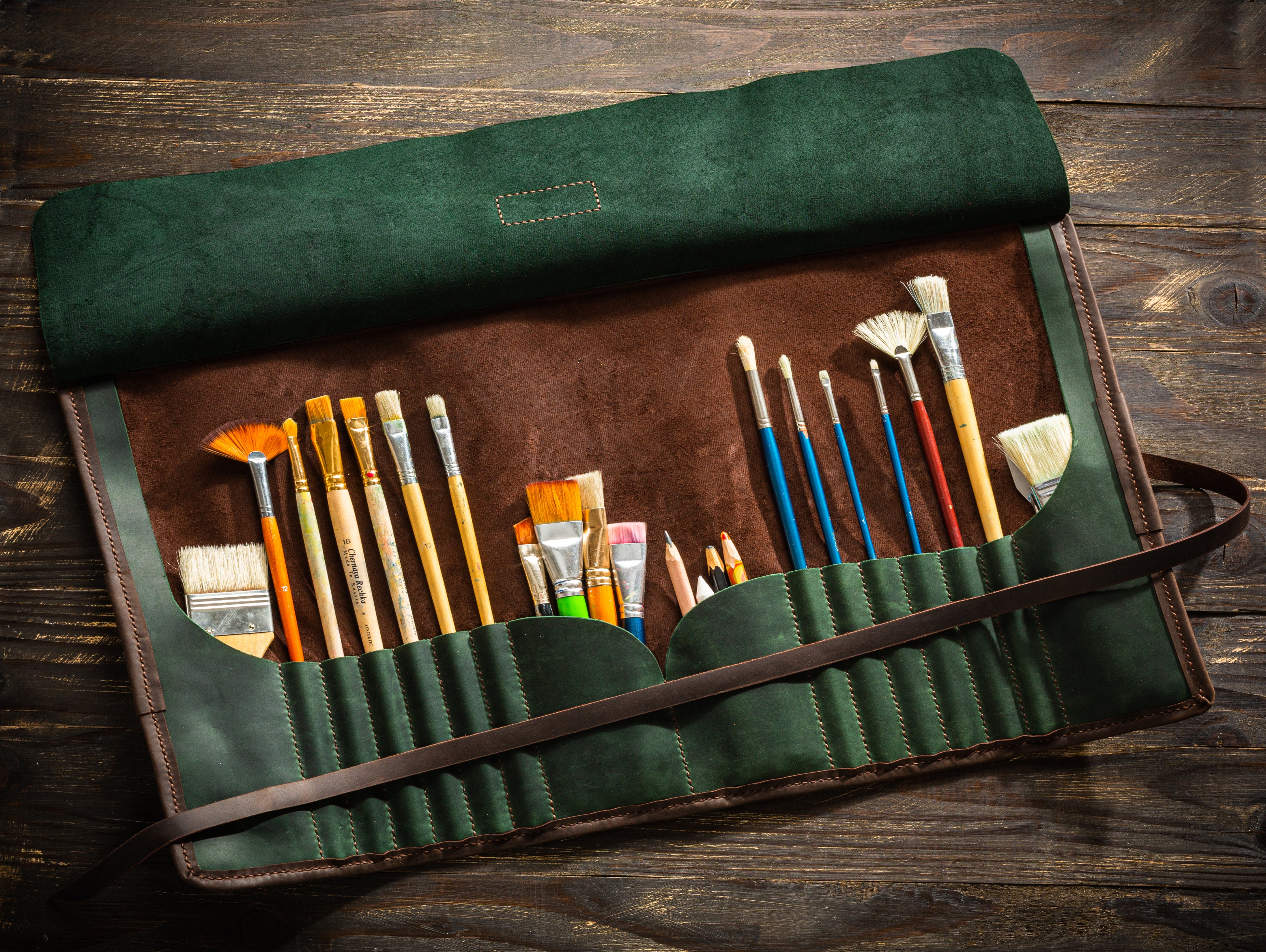 Open forest green leather brush roll for artists with personalized tag and tools inside