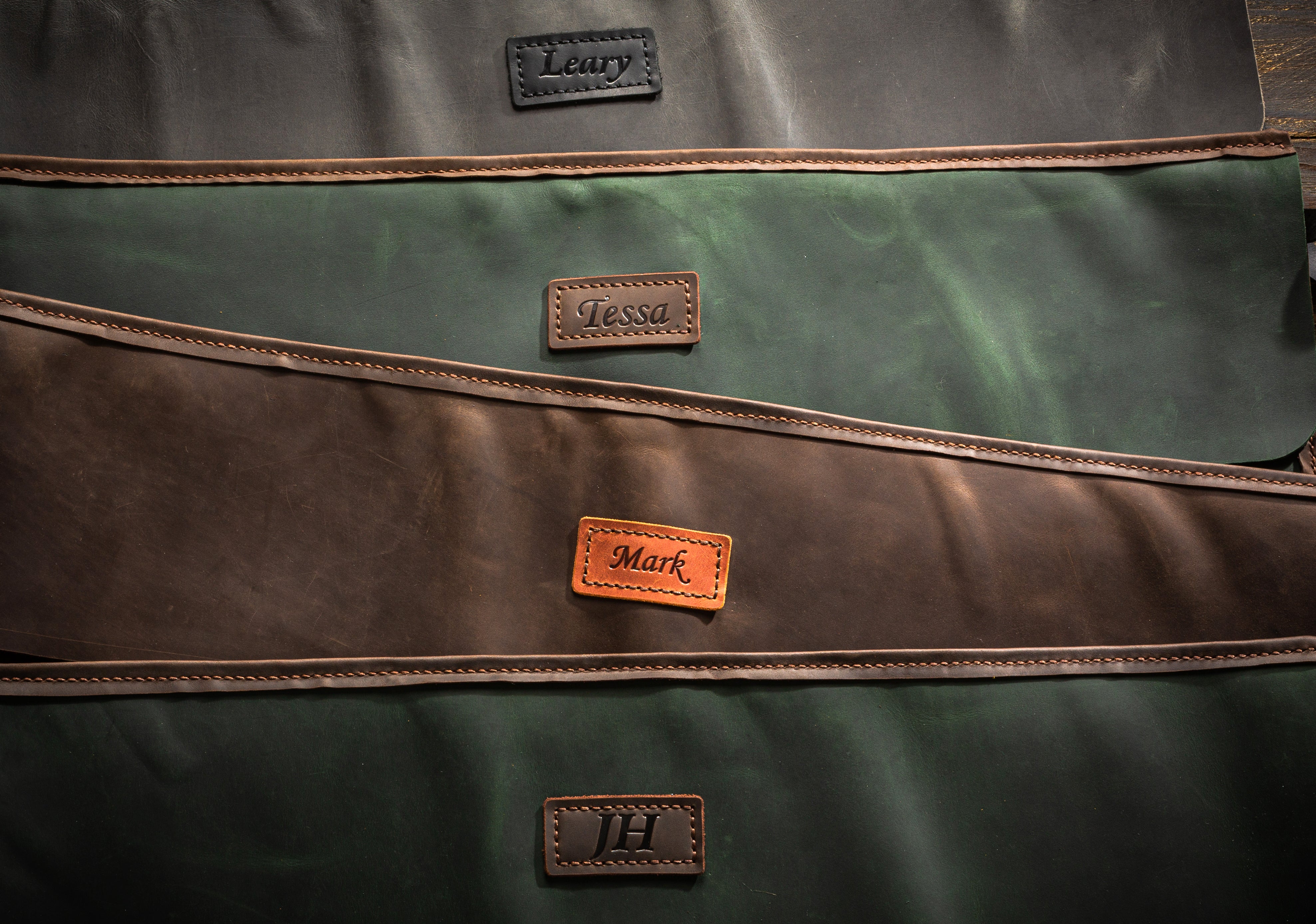 Personalized leather name tags for artist brush rolls with paint tubes, brush, and metal initials