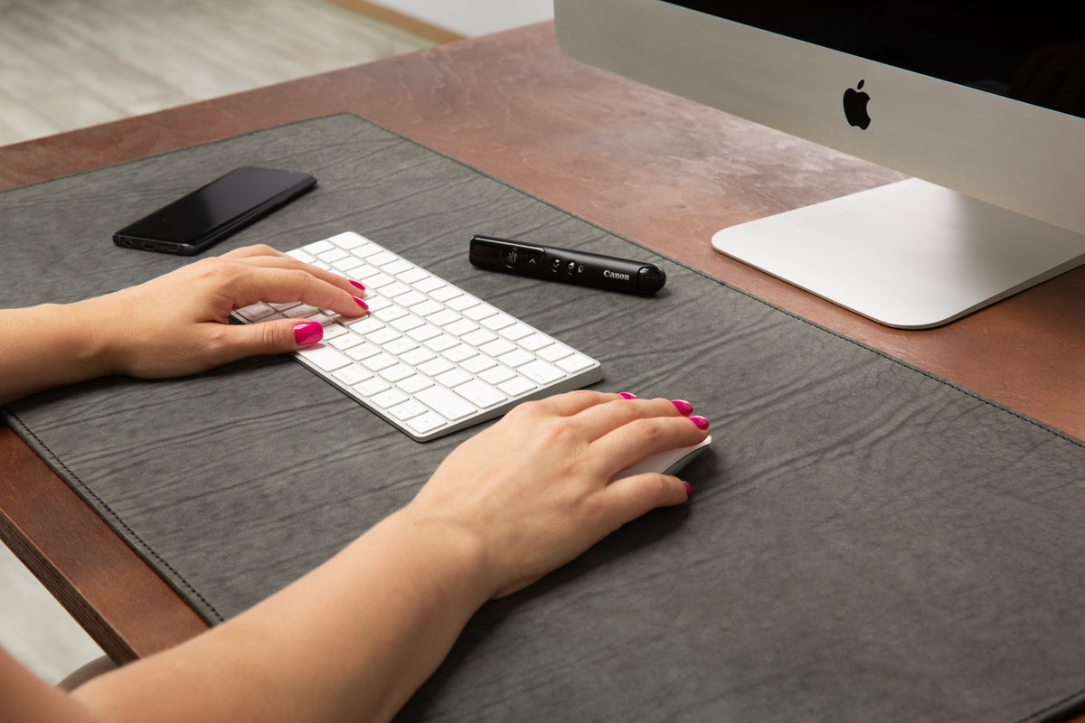 Close-up of a gray leather desk pad with celeste blue stitching and personalized monogram embossing