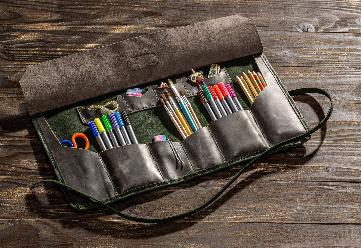 Open gray and olive green leather artist tool roll with pencils, brushes, markers and personalized name tag