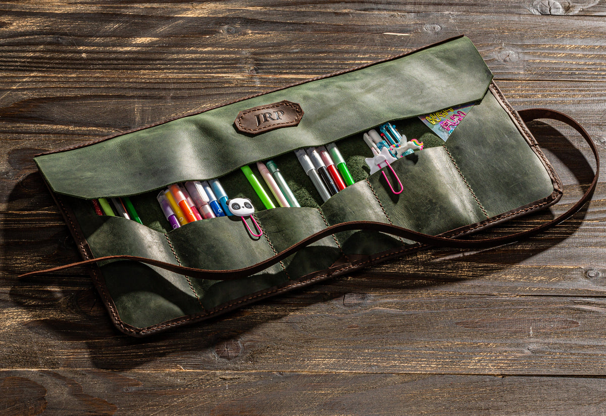 Compact olive green and brown leather artist tool roll with pockets for pens, pencils and creative supplies