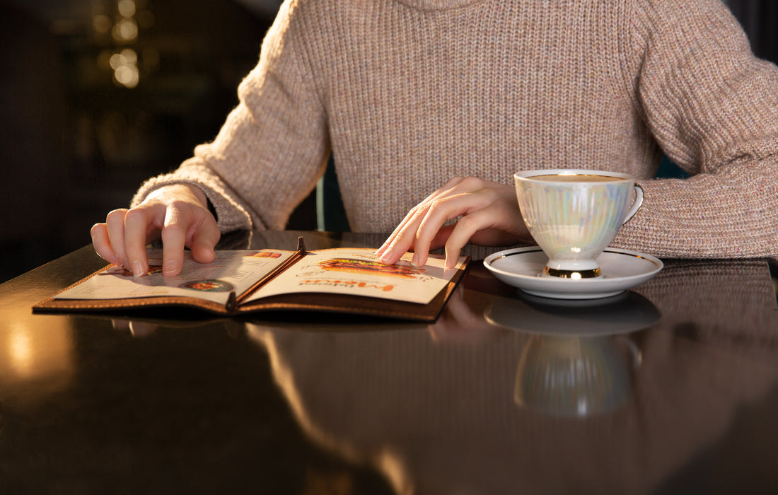 Close-up of hands flipping through a menu in a brown leather folder