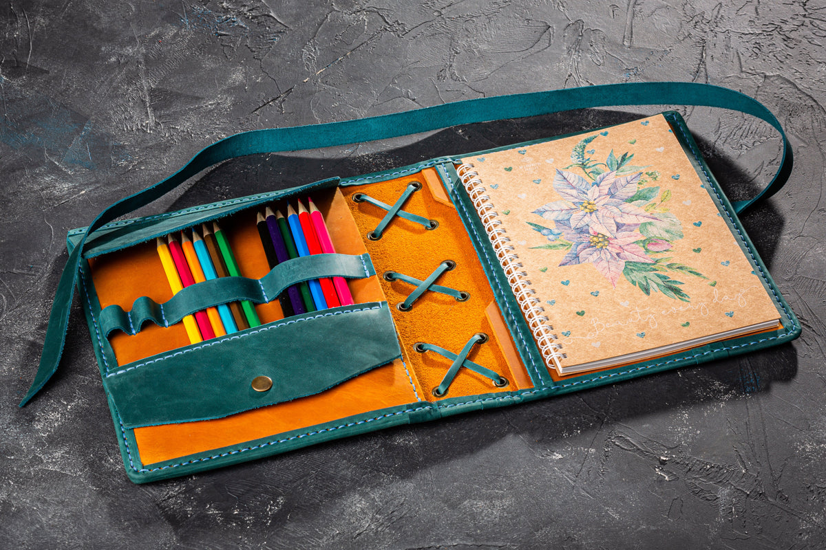 Open wheat yellow and teal leather artist organizer with colored pencils and A5 sketchbook